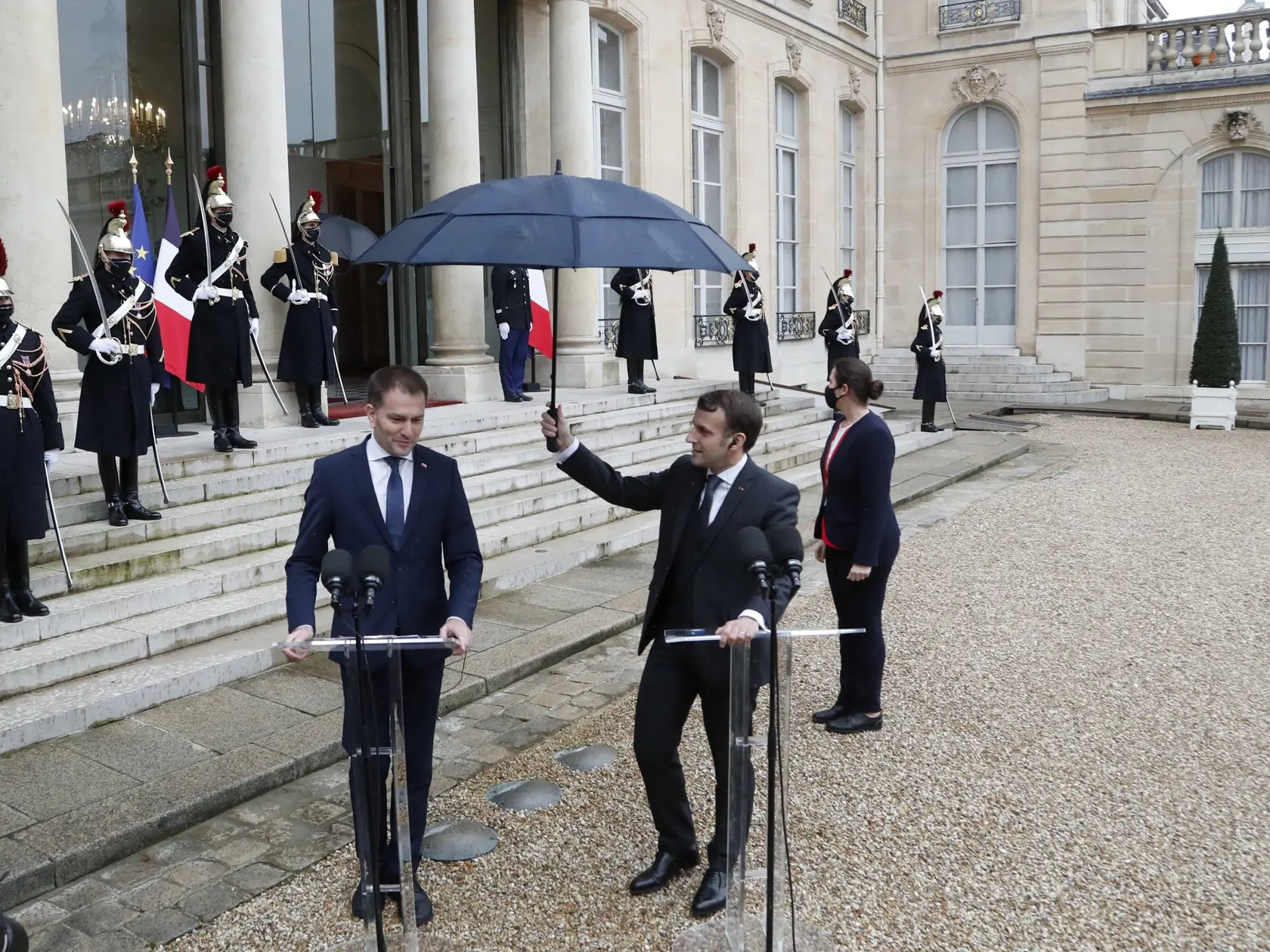 Francúzsky prezident Emmanuel Macron (vpravo) drží dáždnik nad slovenským expremiérom Igorom Matovičom počas vyhlásenia pred spoločným rokovaním 3. februára 2021 v Elyzejskom paláci v Paríži.