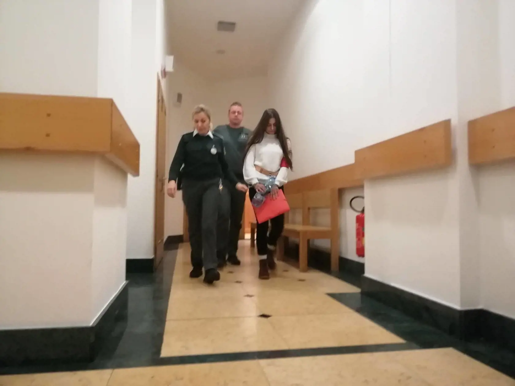 Mladú Juditu odvádzajú z pojednávacej miestnosti.