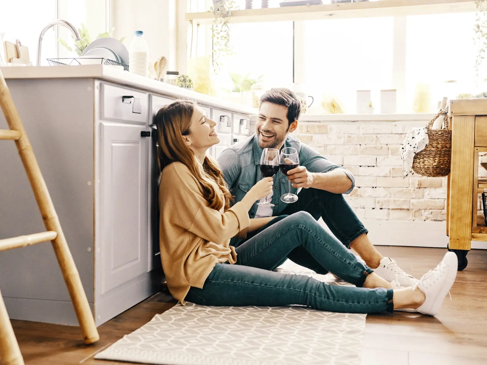 Love is in the air. Beautiful young couple drinking wine while sitting on the kitchen floor at home