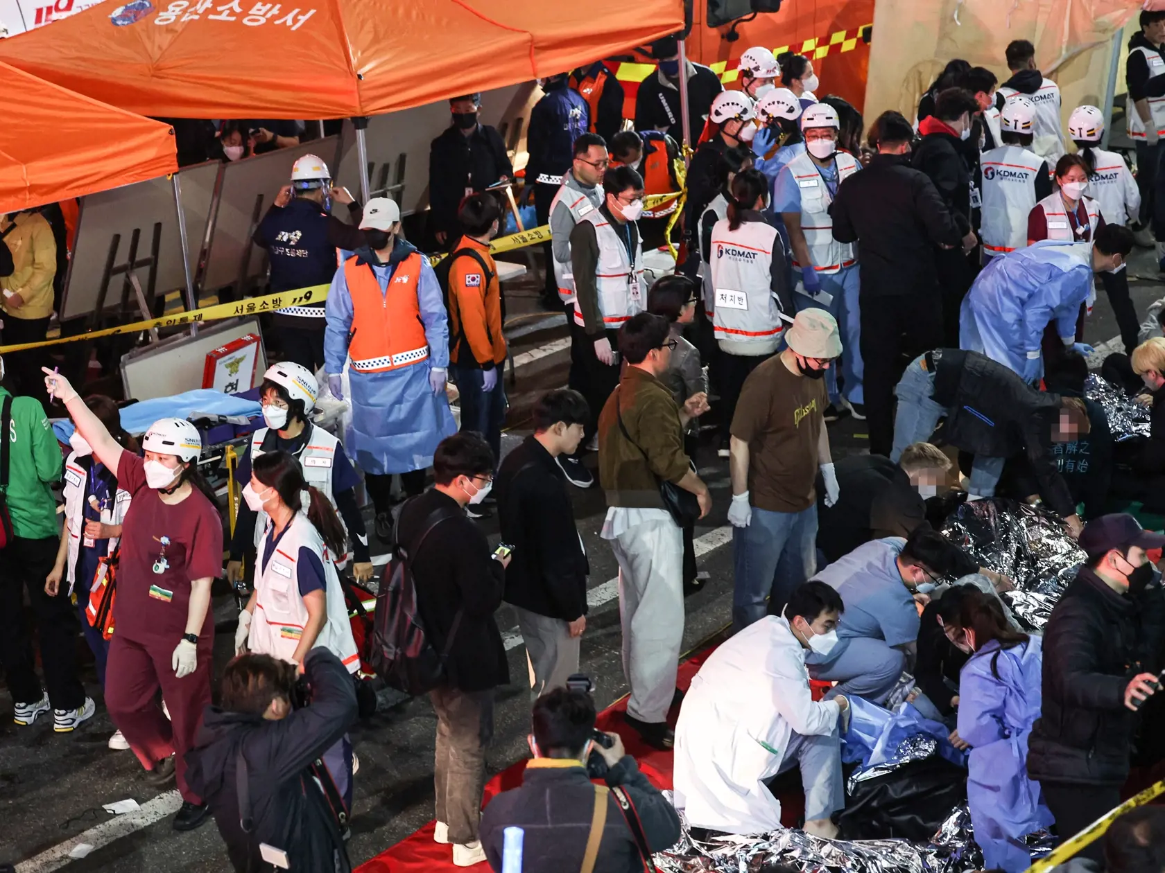 Záchranári ošetrujú na ulici ľudí, ktorí sa zranili počas tlačenice na oslavách Halloweenu v juhokórejskom meste Soul v sobotu večer miestneho času 29. októbra 2022.