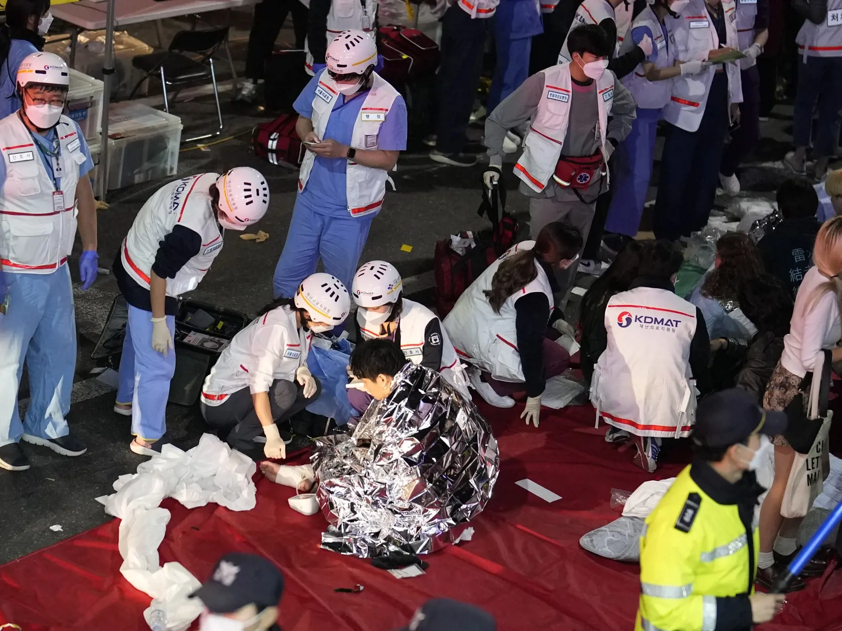 Záchranné zložky ošetrujú na ulici zranené osoby po tlačenici, ku ktorej došlo počas osláv Halloweenu v juhokórejskom meste Soul v sobotu večer miestneho času 29. októbra 2022.