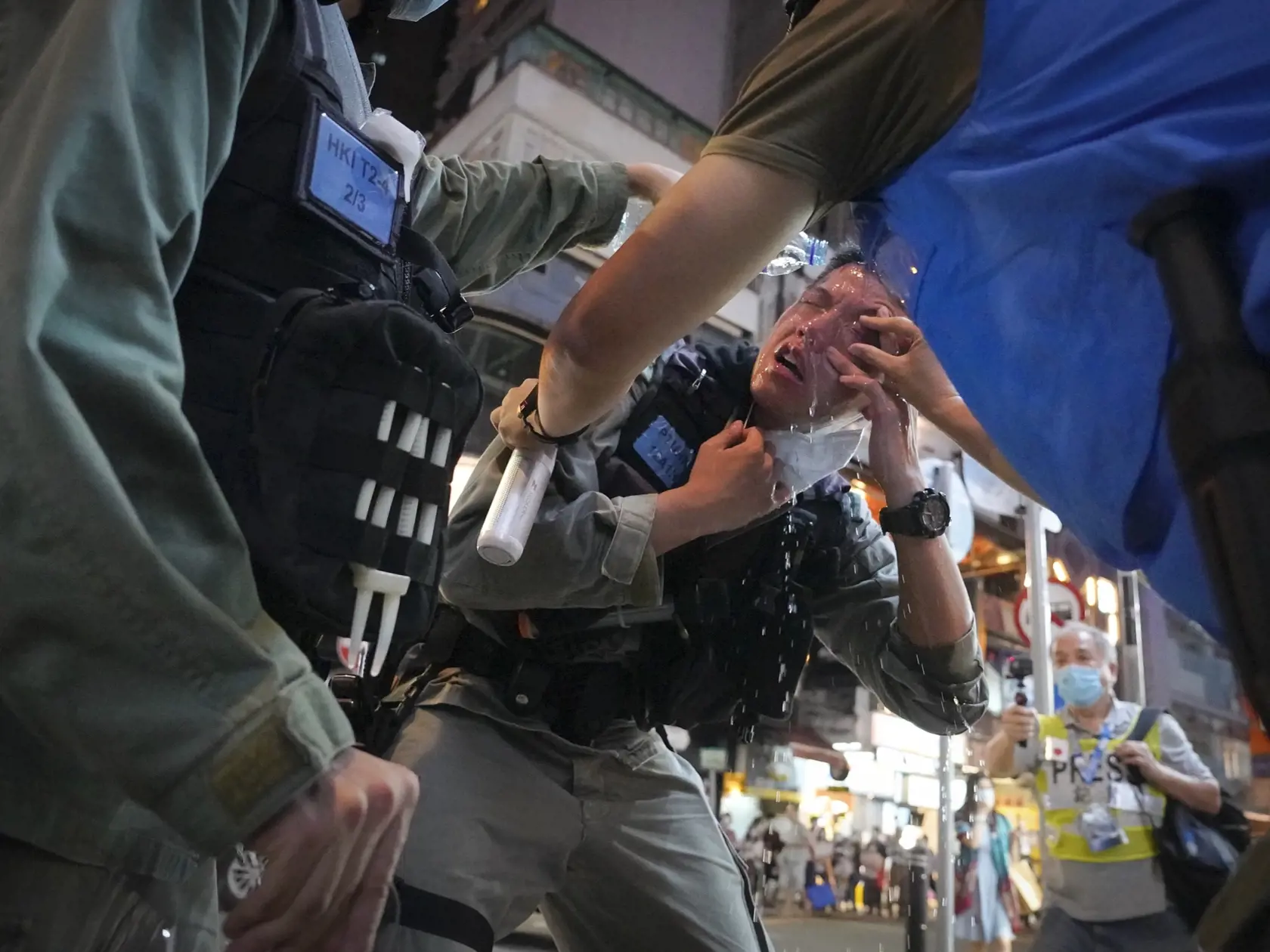 JB 12 Hongkong - Príslušník hongkongských poriadkových síl si vyplachuje oči s pomocou ďalších policajtov po tom, ako bol zasiahnutý paprikovým sprejom počas protestu demonštrantov na Causeway Bay v Hongkongu 12. júna 2020. Protesty zvolané pri príležitosti pripomenutia si prvého výročia od začiatku prodemokratických demonštrácií zároveň prichádzajú v čase stúpajúceho napätia v súvislosti s pripravovaným zákonom o národnej bezpečnosti, ktorý minulý týždeň schválil čínsky parlament. FOTO TASR/AP 