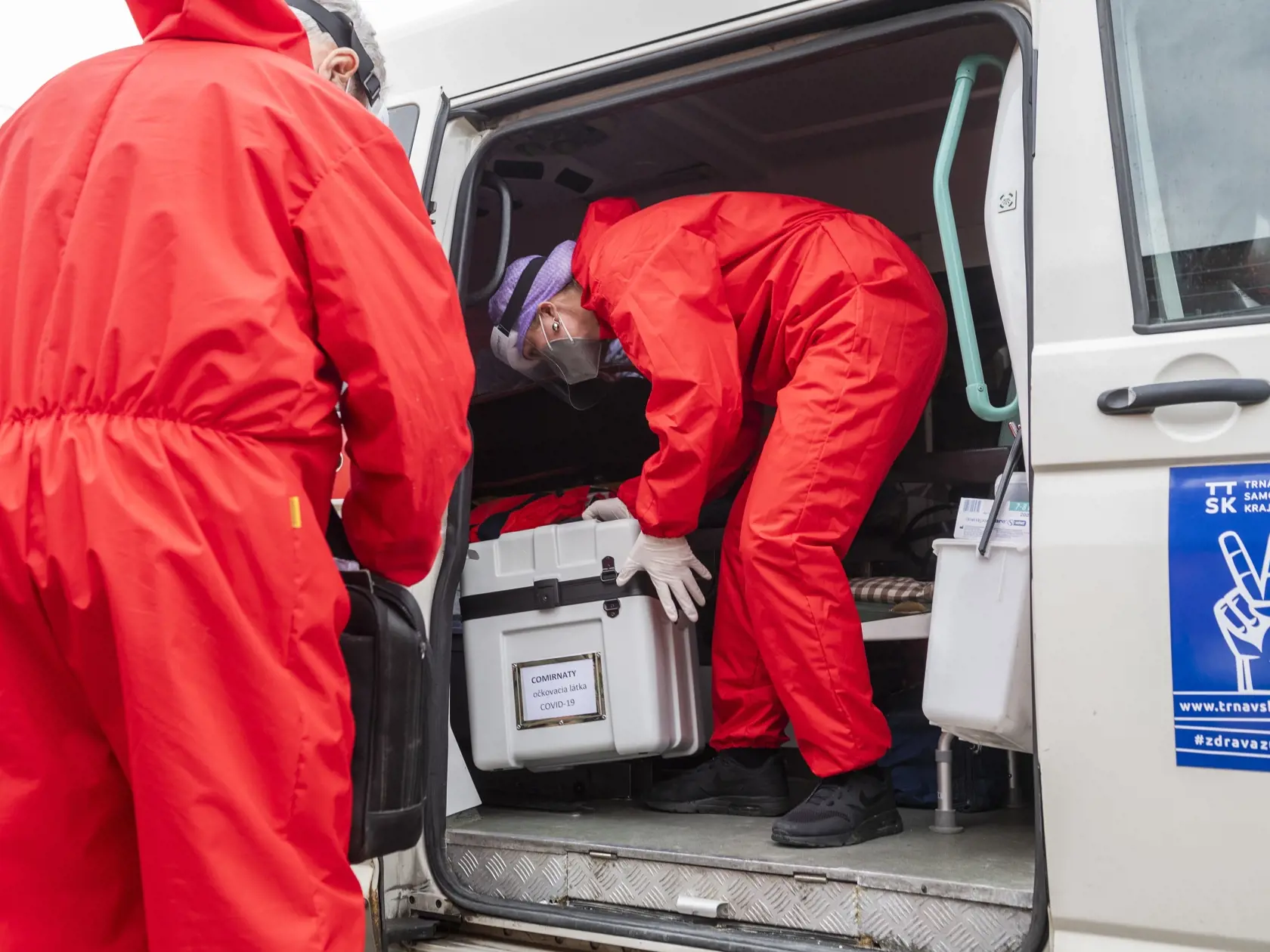 Na snímke členovia mobilnej očkovacej jednotky odnášajú mobilnú chladničku s vakcínou od spoločností Pfizer/BionTech proti ochoreniu Covid-19 po zaočkovaní pacientky počas tlačovej konferencie k výjazdovému očkovaniu imobilných pacientov v domácnostiach v trnavskej mestskej časti Modranka 16. apríla 2021. FOTO TASR - Jaroslav Novák	
