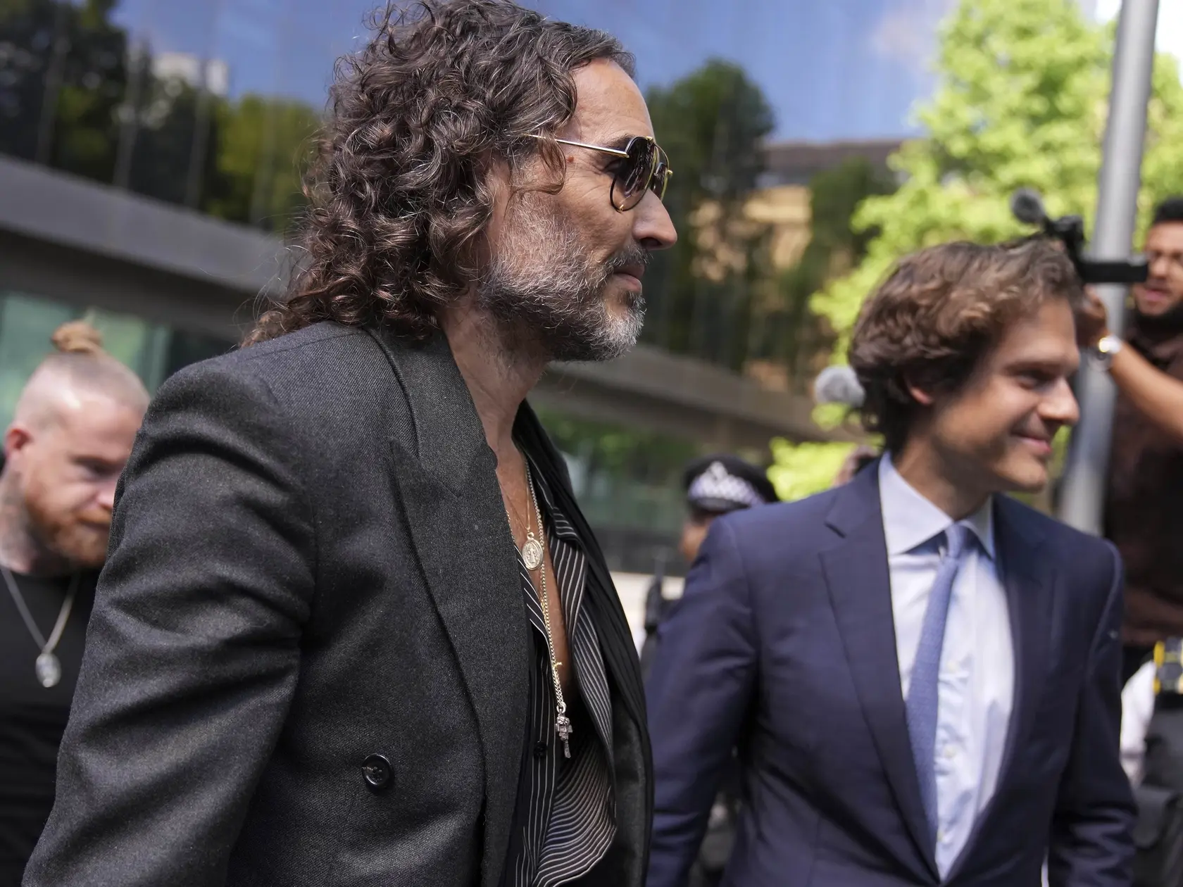 Britský komik, herec a bývalý moderátor Russell Brand (vľavo) prichádza na súd v Londýne 30. mája 2025, kde bude pokračovať ďalšie pojednávanie v procese s ním pre obvinenia zo znásilnenia a ďalších sexuálnych trestných činov.