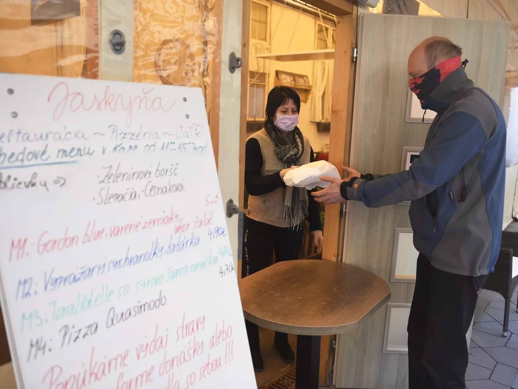 Na snímke čašníčka vydáva zabalený obed z reštaurácie zákazníkovi v centre Košíc kvôli zatvoreným reštauráciam 16. marca 2020. FOTO TASR - František Iván