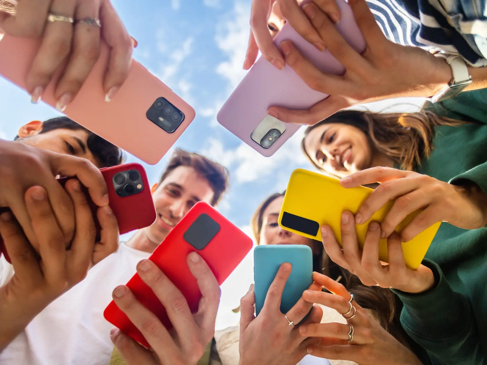 Young,Group,Of,People,Using,Mobile,Phone,Device,Standing,Together