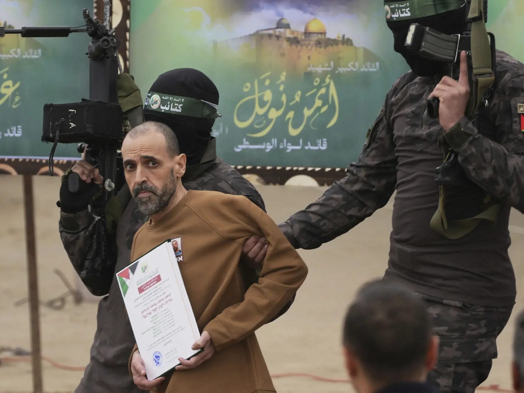 Unesený izraelský rukojemník Elih Šarabi, ktorý bol v zajatí od útoku palestínskeho militantného hnutia Hamas na juh Izraela zo 7. októbra 2023, pózujú s bojovníkmi Hamasu pred svojím odovzdaním Červenému krížu v meste Dajr al-Balah v Pásme Gazy v sobotu 8. februára 2025.