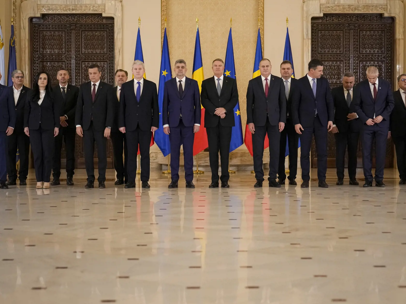 Nový rumunský premiér Marcel Ciolacu (uprostred vľavo), členovia jeho vlády a rumunský prezident Klaus Iohannis (uprostred vpravo) pózujú po zložení sľubu v prezidentskom paláci v Bukurešti v pondelok 23. decembra 2024.