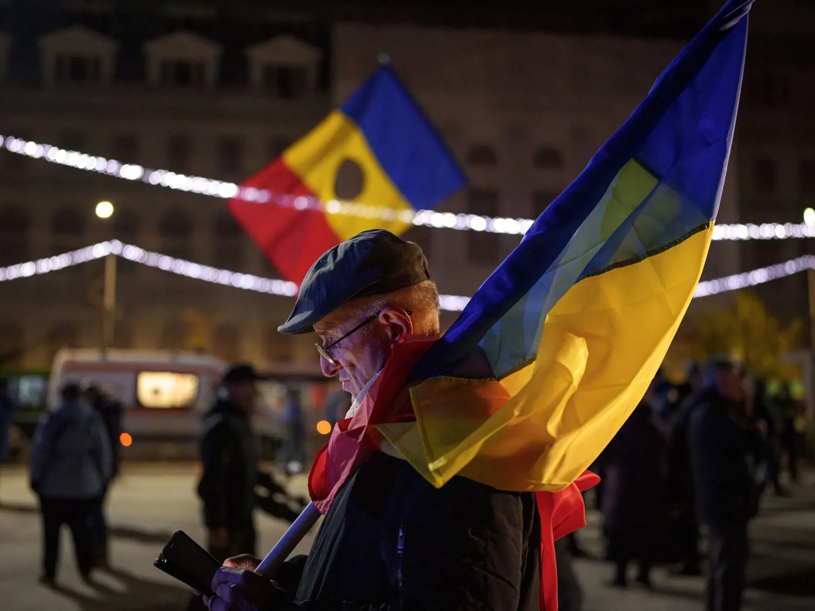 Muž, ktorý drží rumunskú vlajku, kontroluje svoj mobilný telefón na proeurópskom zhromaždení pred 2. kolom prezidentských volieb v Bukurešti vo štvrtok 5. decembra 2024. Rumunský ústavný súd anuloval v piatok výsledky prvého kola prezidentských volieb. K takémuto rozhodnutiu dospel po tom, ako boli odtajnené dokumenty spravodajských služieb, z ktorých vyplýva, že Rusko viedlo na internete koordinovanú kampaň na podporu nezávislého krajne pravicového kandidáta Calina Georgesca, víťaza prvého kola volieb. Rozhodnutie súdu je konečné a znamená, že voľby sa musia zopakovať. V nedeľu sa pritom malo konať ich druhé kolo.