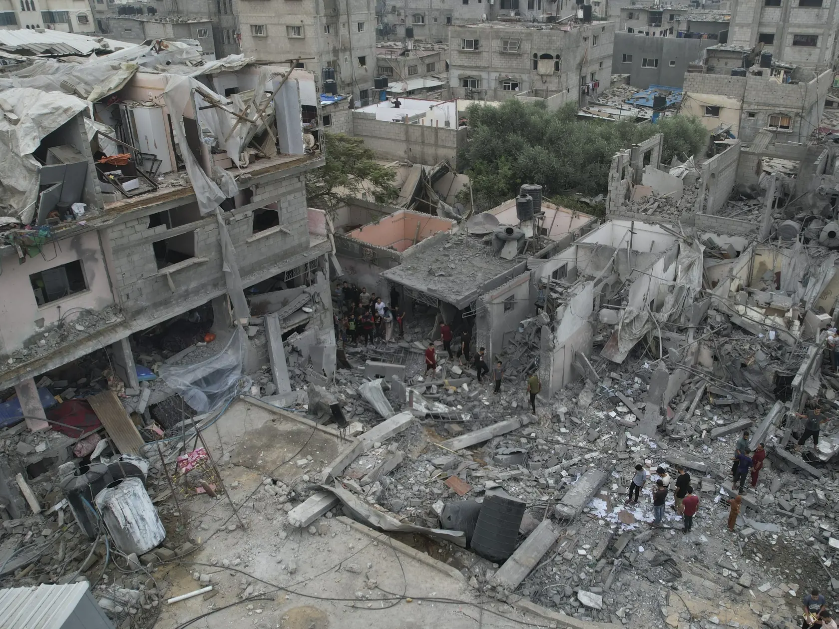 Palestínčania kráčajú okolo budov zničených počas izraelského bombardovania 29. októbra 2023 v utečeneckom tábore Nusseirat.