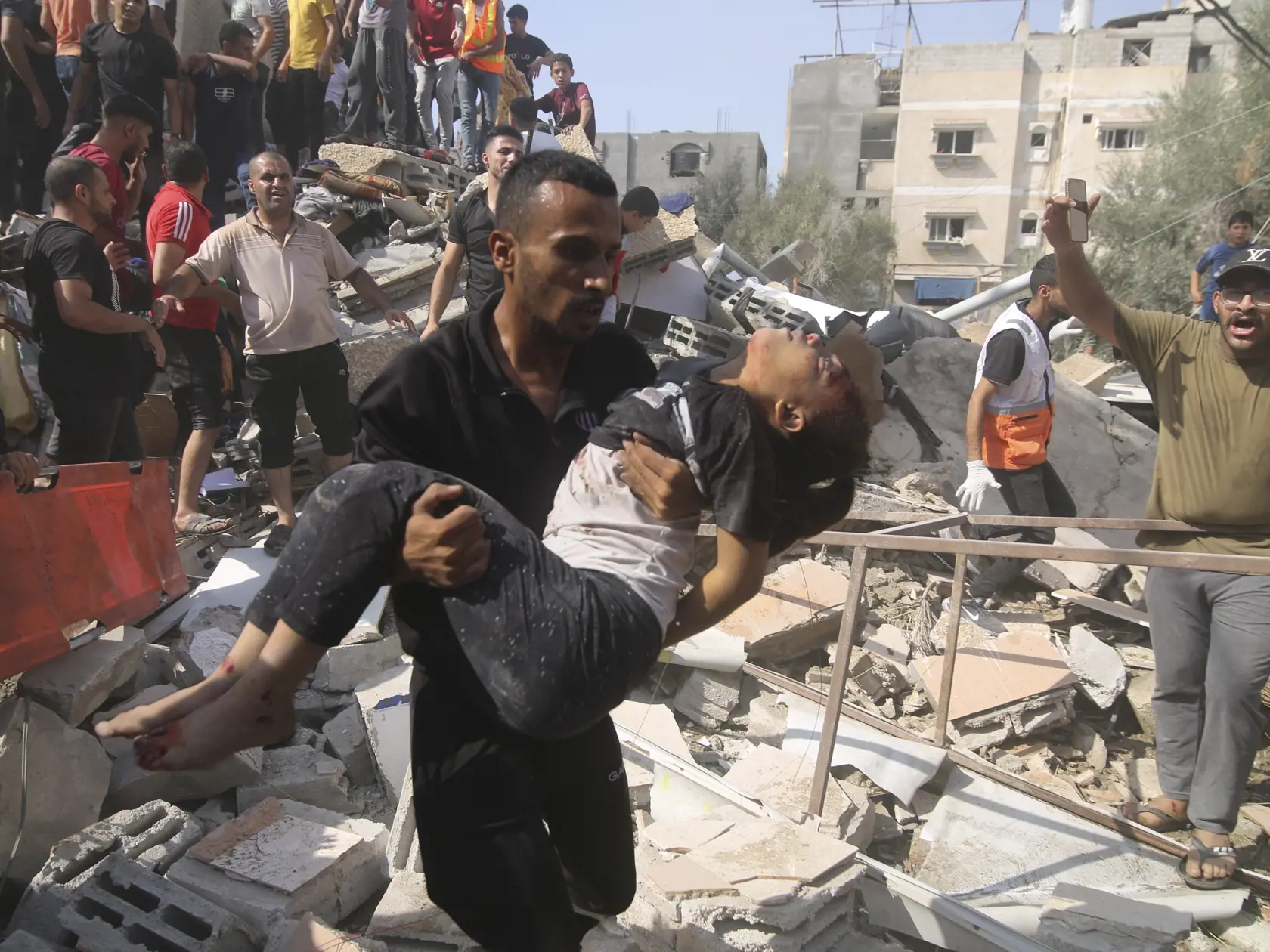 Muž nesie na rukách palestínske dievča, ktoré vytiahli z trosiek zničeného domu po izraelskom bombardovaní pásma Gazy v Rafahu 23. októbra 2023.
