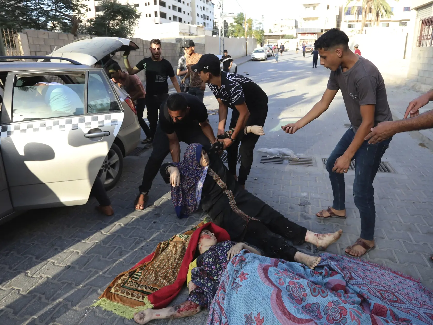 Palestínčania transportujú zranené ženy, ktoré našli ležať na ulici po izraelskom leteckom útoku na Gazu 25. októbra 2023.