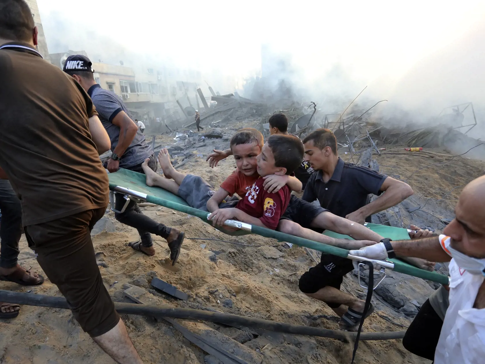 Palestínčania evakuujú dvoch zranených chlapcov, ktorých vyziahli zo zrútenej budovy po izraelskom leteckom útoku na pásmo Gazy 25. októbra 2023.