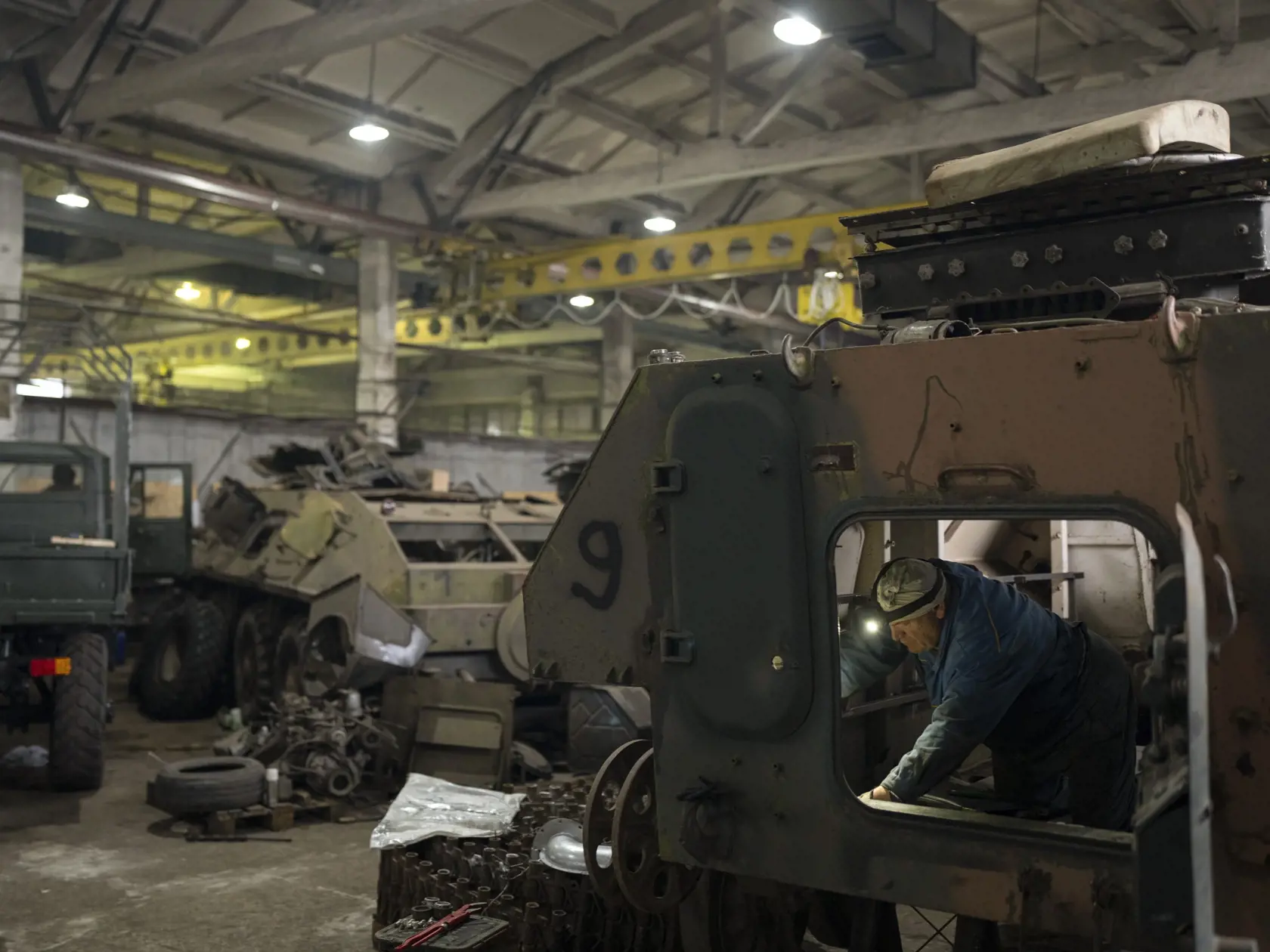 Mechanik opravuje ukrajinské vojenské vozido v opravovni tankov v Kyjevskej oblasti 20. októbra 2023.