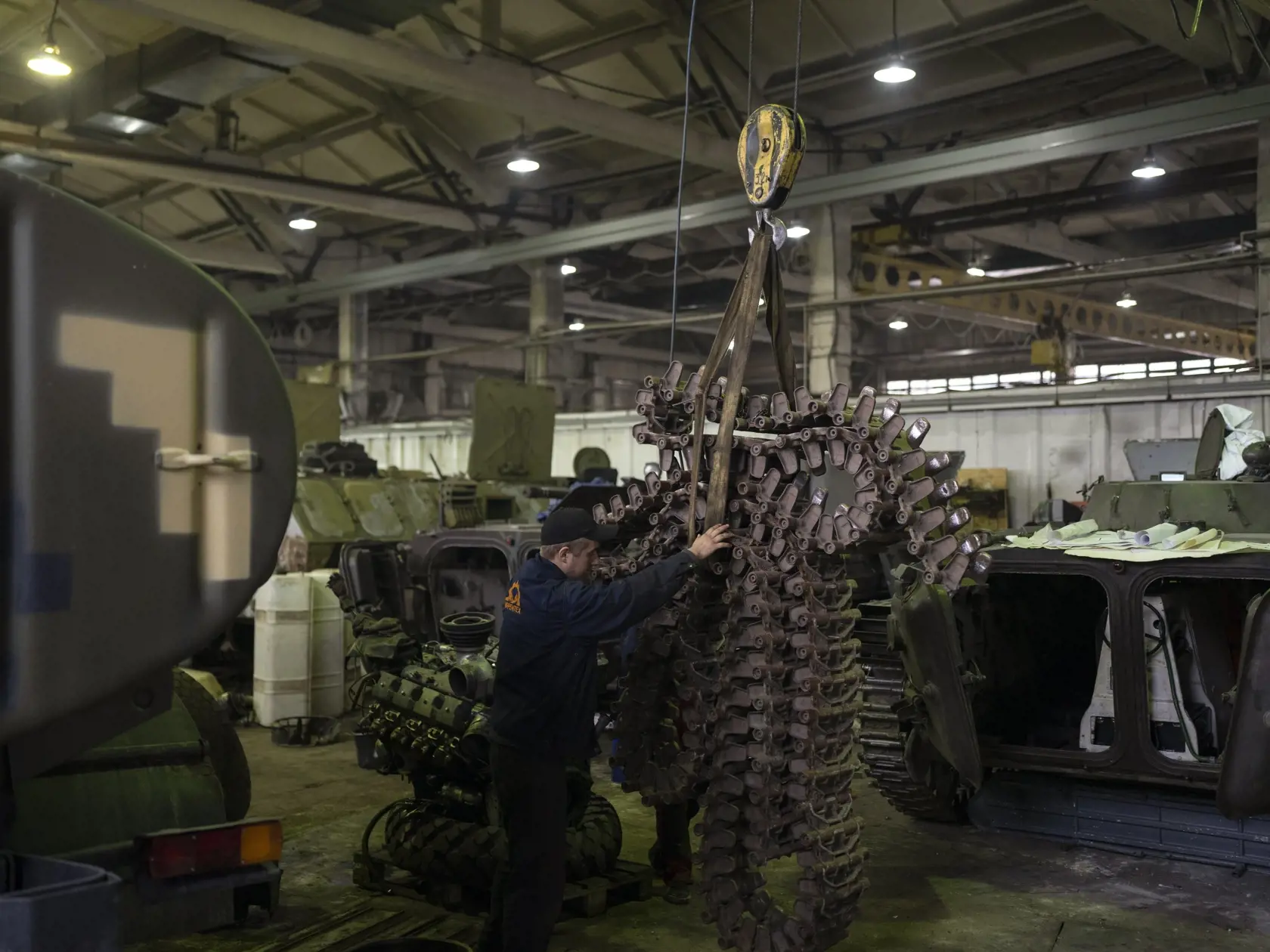 Mechanici presúvajú pás v opravovni tankov v Kyjevskej oblasti 20. októbra 2023.