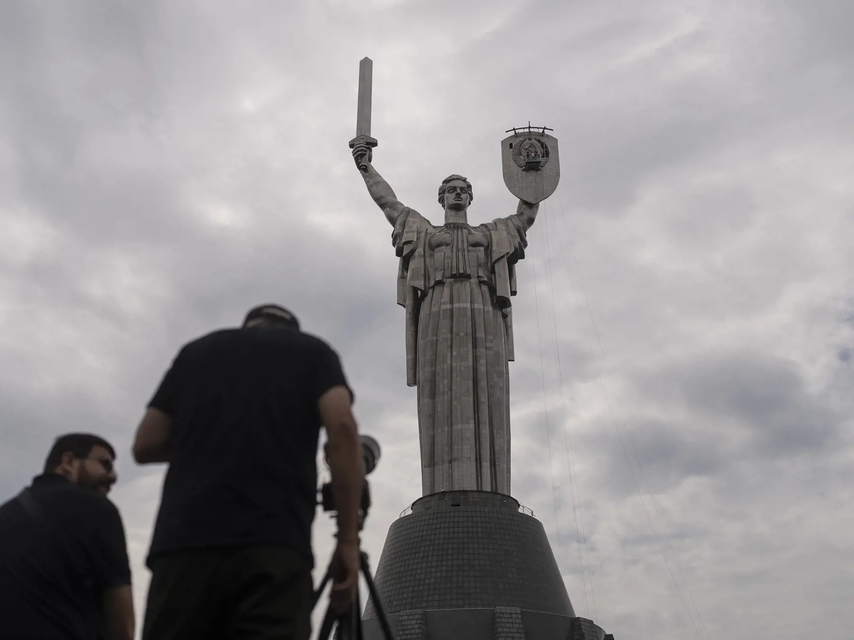 Na snímke fotoreportéri snímajú, ako zamestnanci pripravujú odstránenie sovietskeho znaku zo štítu pamätníka Matka vlasť v Kyjeve na Ukrajine v pondelok 31. júla 2023.
