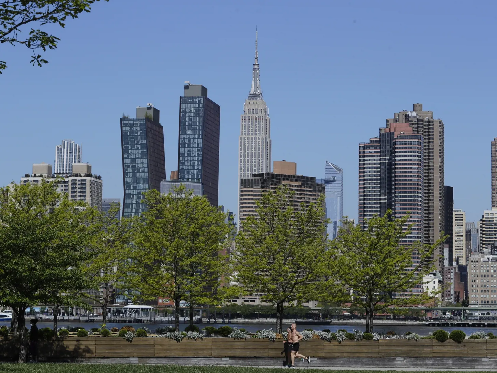 Ľudia bez ochranného rúška behajú v parku Hunters Point Park South s výhľadom na Manhattan v štvrti Queens v New Yorku 14. mája 2020. Spojené štáty patria medzi krajiny, ktoré epidémia koronavírusu postihla najviac.