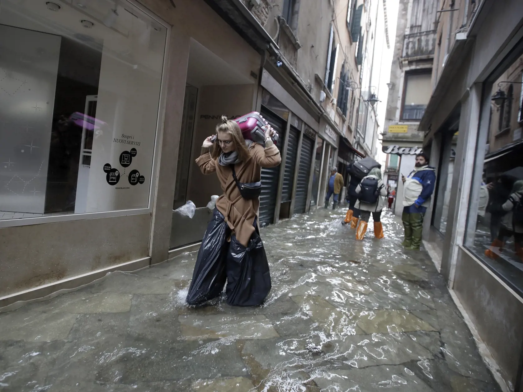 EBE 19 Benátky - Na snímke turiskai s batožinou sa brodí v zpalavenej ulici v Benátkach v dôsledku silného prílivu 13. novembra 2019. Výška vody v meste dosiahla tesne pred polnocou 1,87 metra, k čomu prispel silný vietor. Príliv v benátskej lagúne každoročne vrcholí v priebehu jesene a zimy, keď sa voda prelieva do benátskych ulíc a námestí. Už v roku 2003 sa rozbehol projekt na ochranu mesta pred vysokou vodou, avšak sprevádzajú ho škandály a predlžovanie termínov. Podľa plánu má byť v Benátka