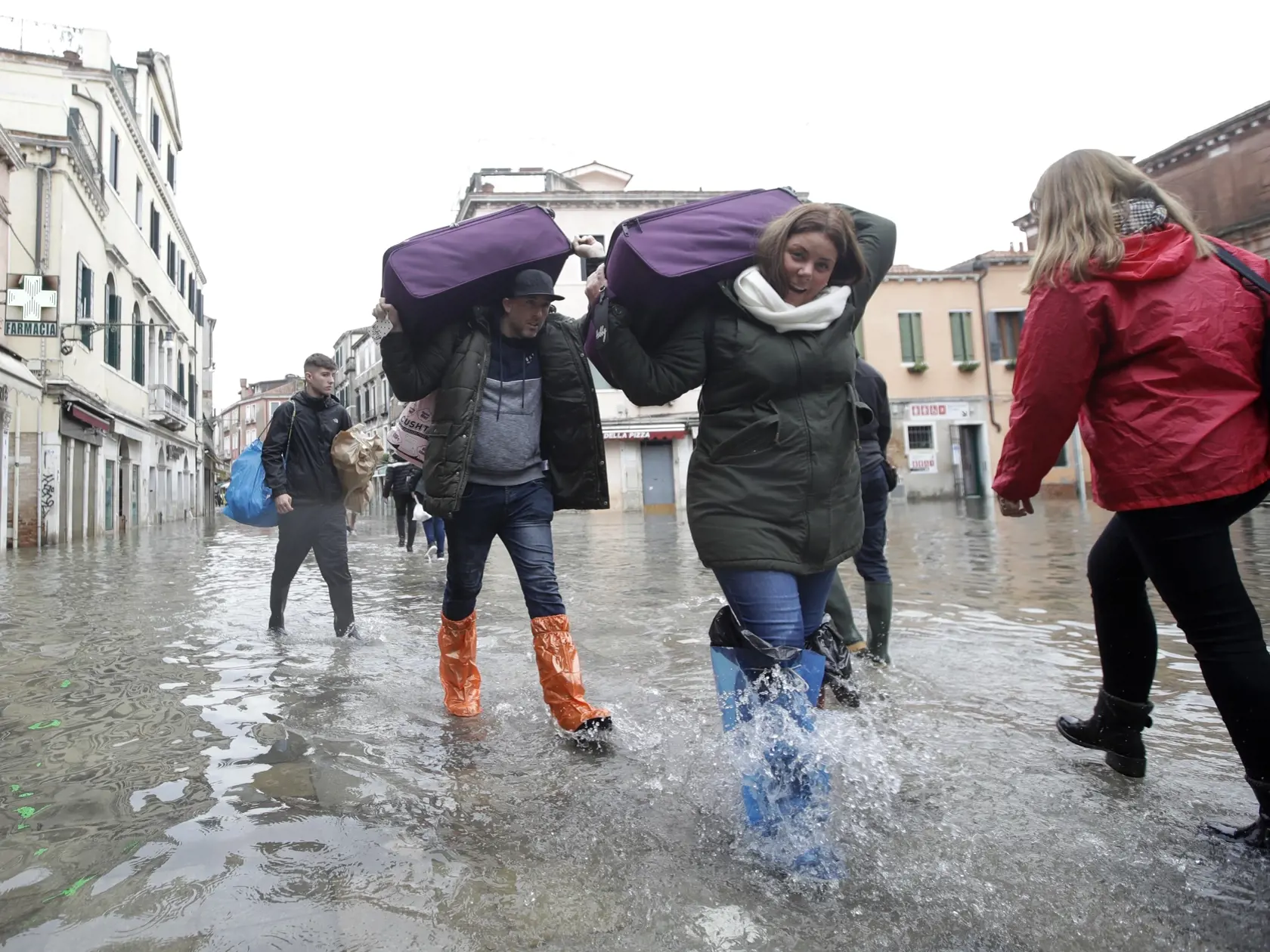 EBE 18 Benátky - Na snímke turisti s batožinou sa brodia v zpalavenej ulici v Benátkach v dôsledku silného prílivu 13. novembra 2019. ýška vody v meste dosiahla tesne pred polnocou 1,87 metra, k čomu prispel silný vietor. Príliv v benátskej lagúne každoročne vrcholí v priebehu jesene a zimy, keď sa voda prelieva do benátskych ulíc a námestí. Už v roku 2003 sa rozbehol projekt na ochranu mesta pred vysokou vodou, avšak sprevádzajú ho škandály a predlžovanie termínov. Podľa plánu má byť v Benátkac