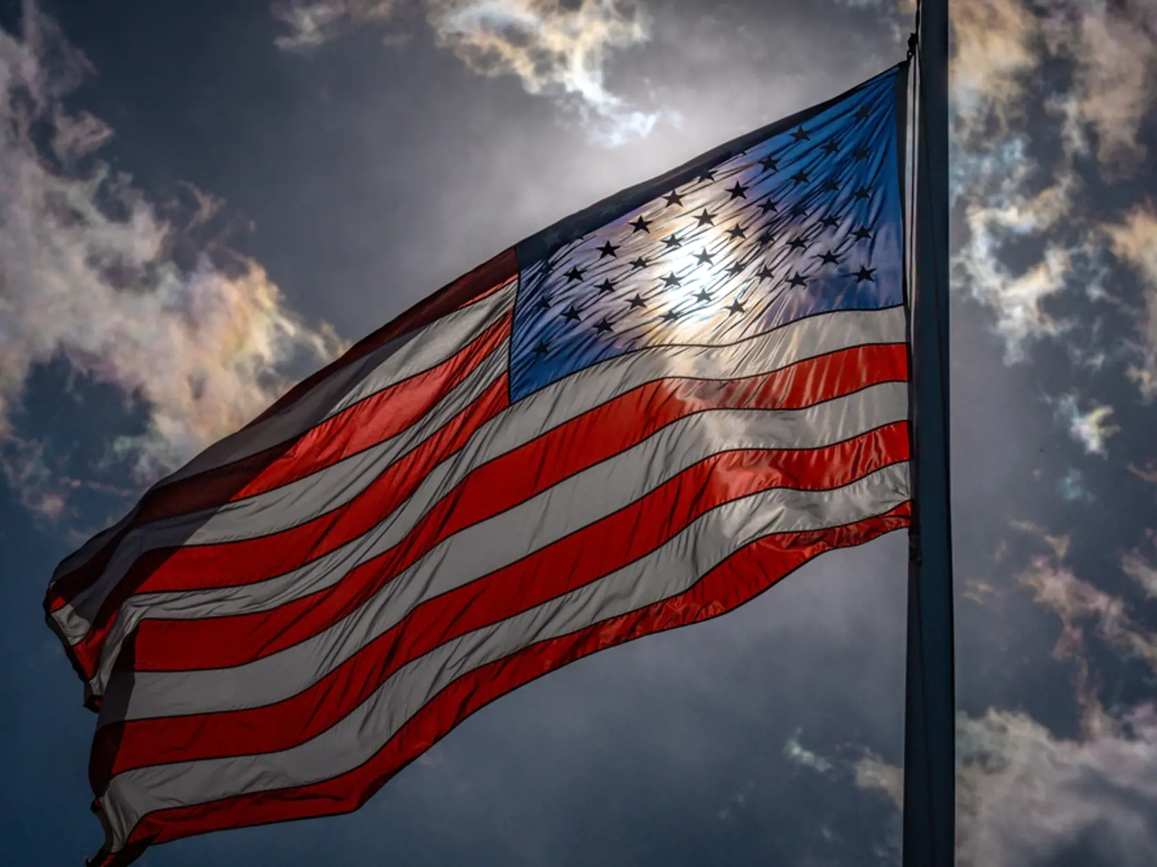 American election and vote concept. US Flag. Waving american flag on dark dramatic sky. USA flag waving near sun.