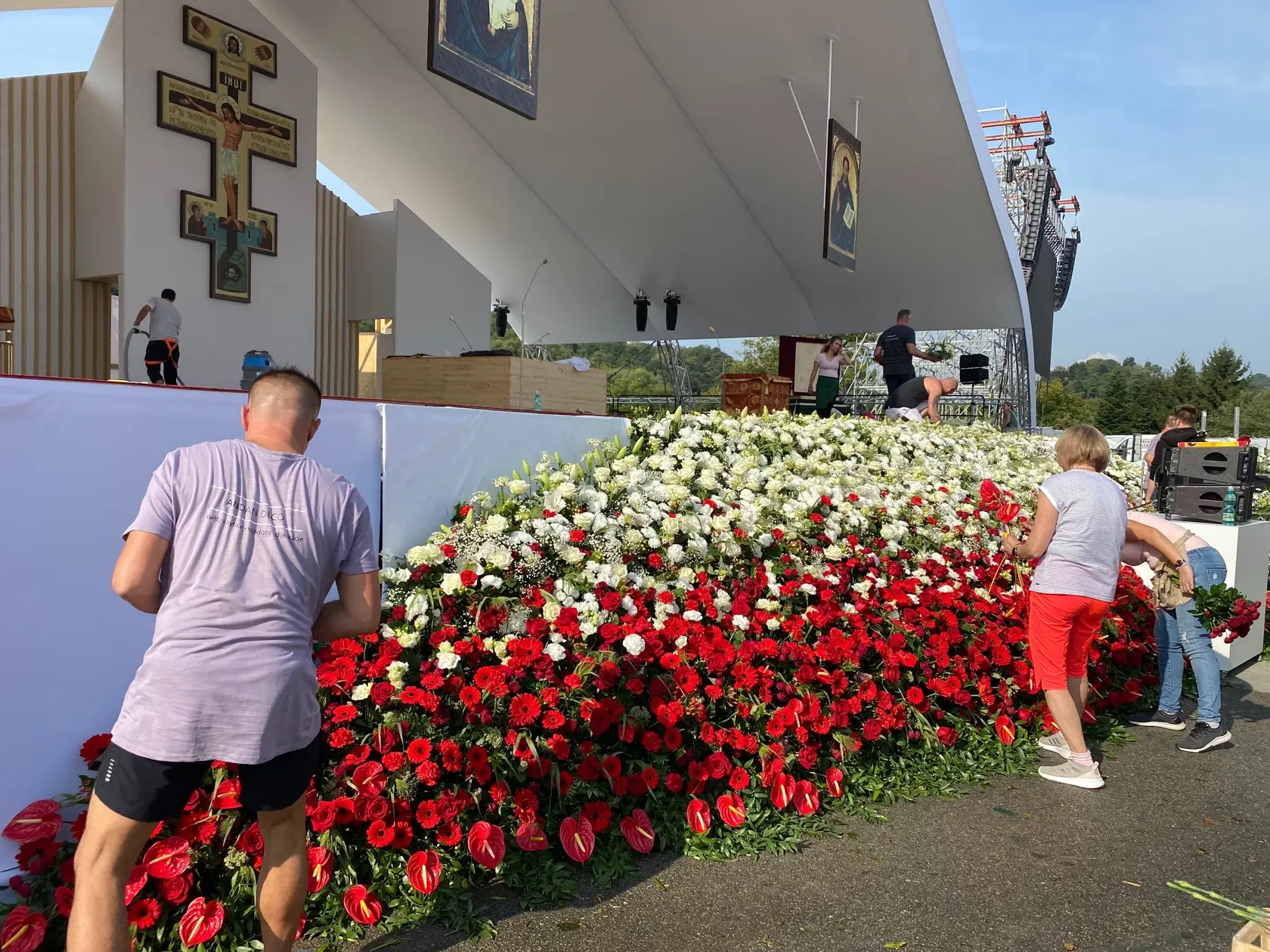 Prípravy liturgického priestoru - kvetinová výzdoba je ladená do bielej a červenej.