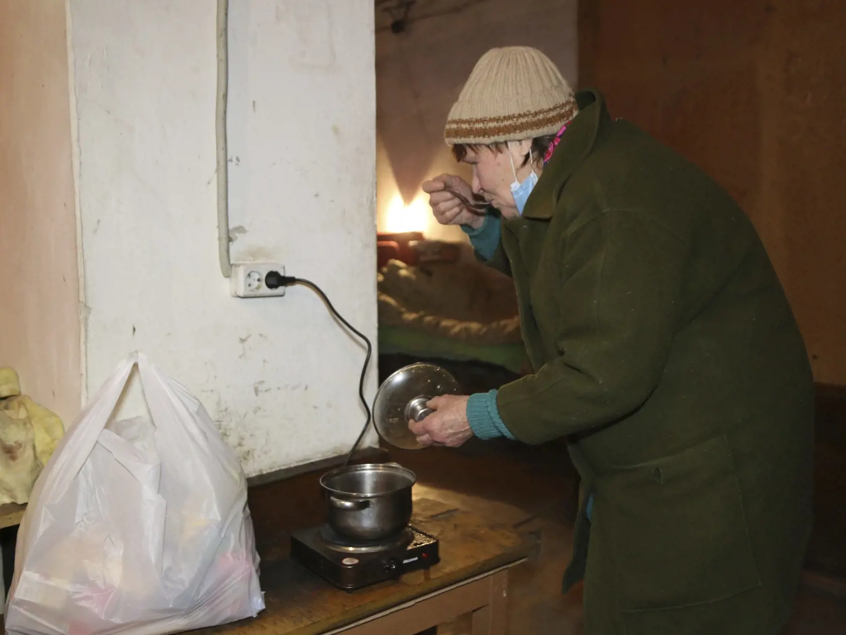 Galina varí polievku v starom a chladnom protileteckom kryte v dedine Trudivske na predmestí Donecka na východe Ukrajiny v utorok 1. februára 2022.
