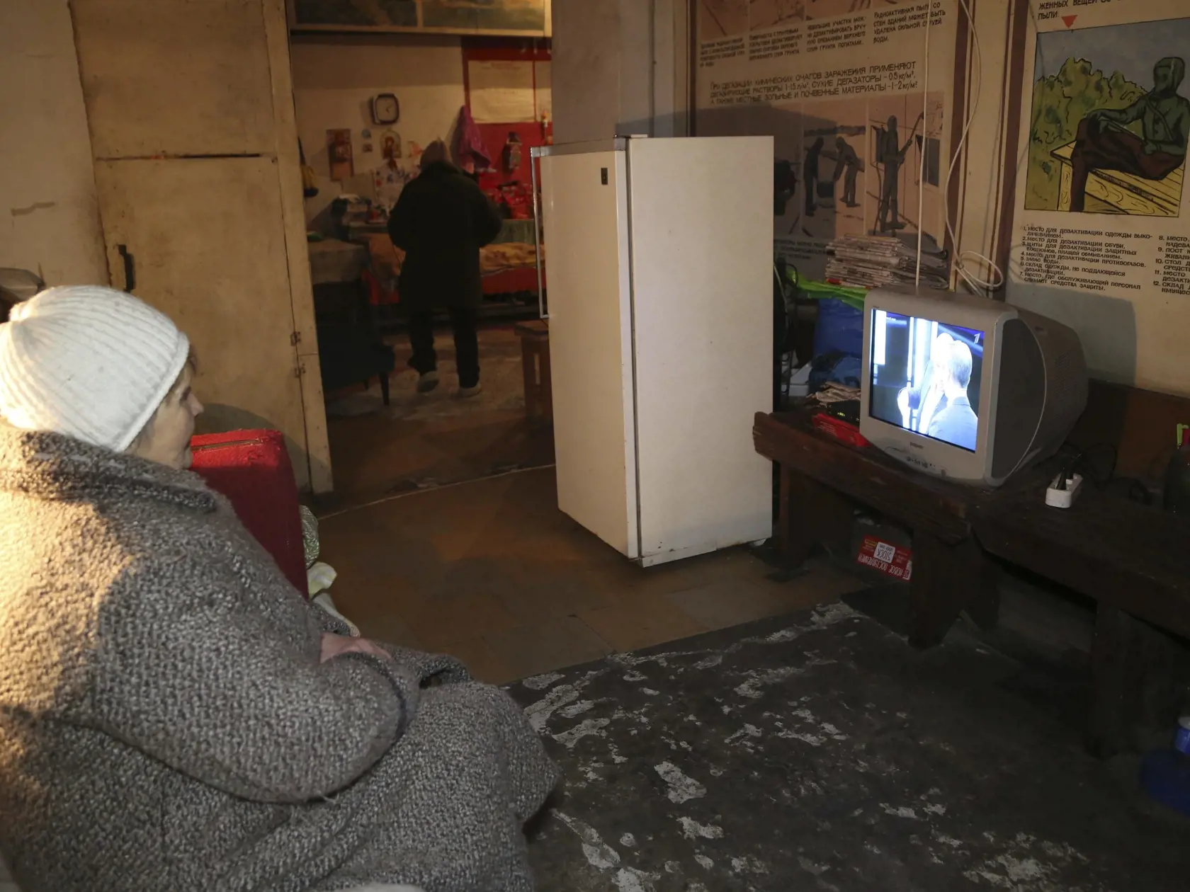 Ljudmila sedí v kabáte a pozerá televízor v starom a chladnom protileteckom kryte v dedine Trudivske na predmestí Donecka na východe Ukrajiny v utorok 1. februára 2022. Deväť miestnych obyvateľov žije v kryte po tom, čo prišli o strechu nad hlavou počas ostreľovania územia, ktoré kontrolujú proruskí separatisti.