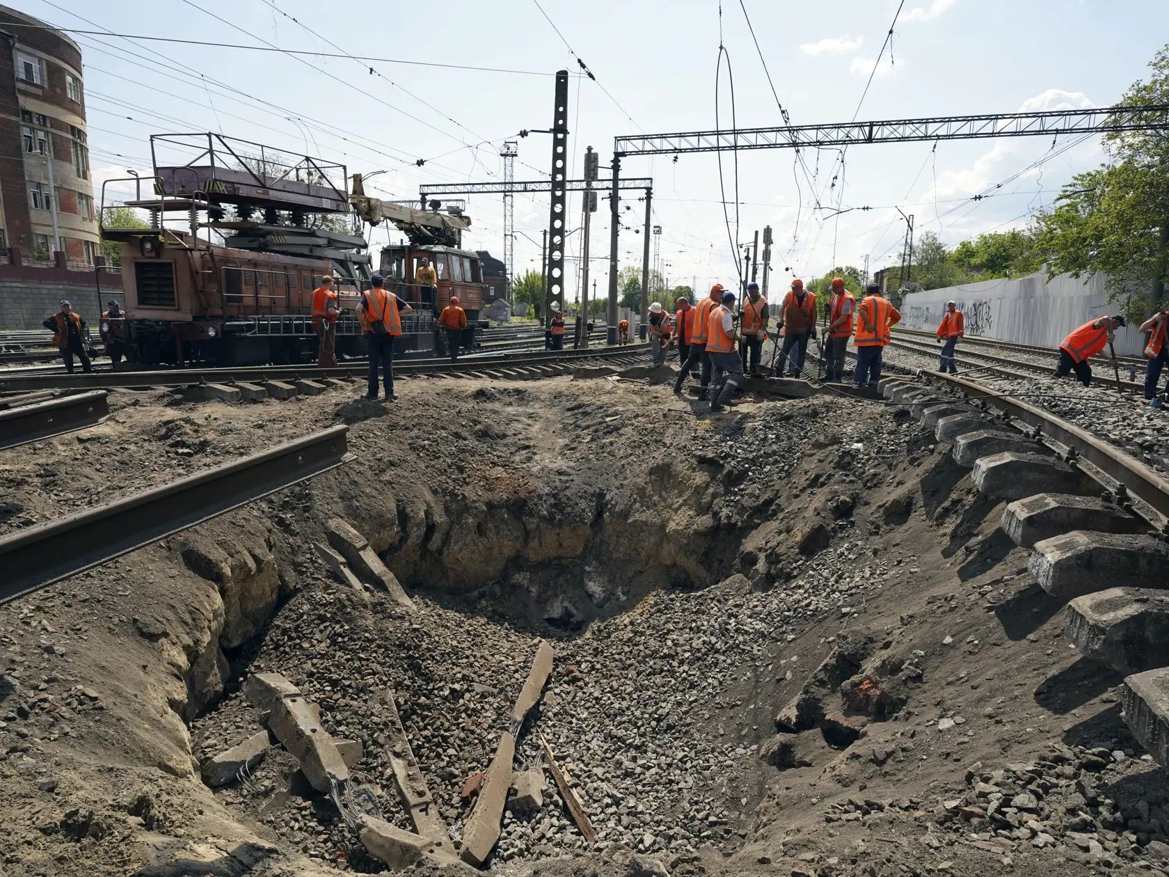Robotníci opravujú železnicu, ktorá bola poškodená pri ruskom raketovom útoku neďaleko hlavnej železničnej stanice, uprostred je kráter po rakete, v nedeľu 15. mája 2023 v ukrajinskom Charkove.