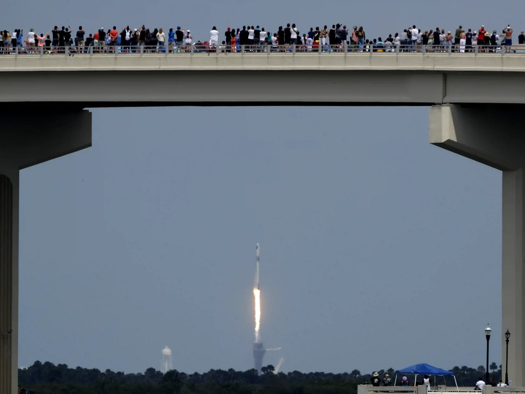 KK2 Titusville - Ľudia sledujú z mosta štart vesmírnej lode Crew Dragon spoločnosti SpaceX s ľudskou posádkou z Mysu Canaveral na americkej Floride, 30. mája 2020 vo floridskom meste Titusville.  Ide o prvý kozmický let s ľudskou posádkou so štartom z územia Spojených štátov za takmer desaťročie. Od roku 2011 sa NASA pri doprave svojich astronautov na ISS spoliehala na ruské rakety. Na palube Crew Dragon sú dvaja astronauti - Robert Behnken (49) a Douglas Hurley (53). Crew Dragon vynáša k Medzin