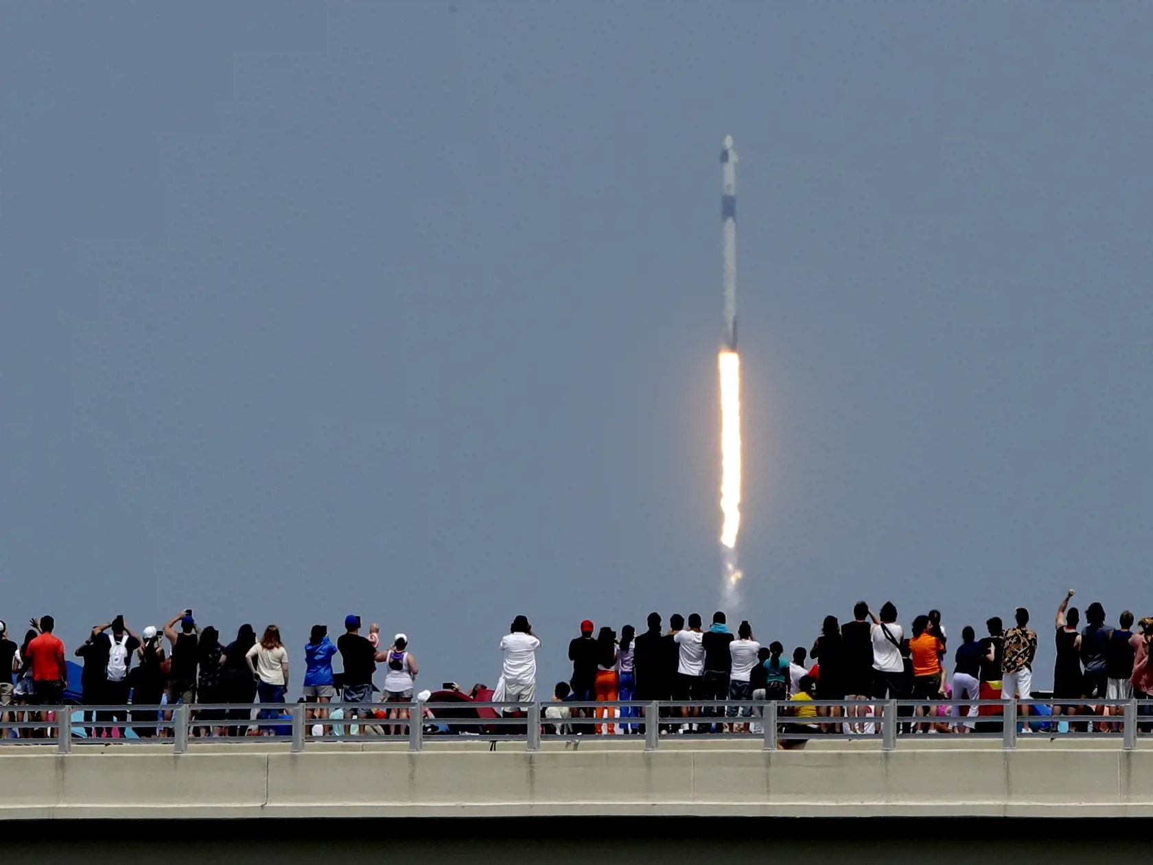 KK1 Titusville - Ľudia sledujú z mosta štart vesmírnej lode Crew Dragon spoločnosti SpaceX s ľudskou posádkou z Mysu Canaveral na americkej Floride, 30. mája 2020 vo floridskom meste Titusville.  Ide o prvý kozmický let s ľudskou posádkou so štartom z územia Spojených štátov za takmer desaťročie. Od roku 2011 sa NASA pri doprave svojich astronautov na ISS spoliehala na ruské rakety. Na palube Crew Dragon sú dvaja astronauti - Robert Behnken (49) a Douglas Hurley (53). Crew Dragon vynáša k Medzin