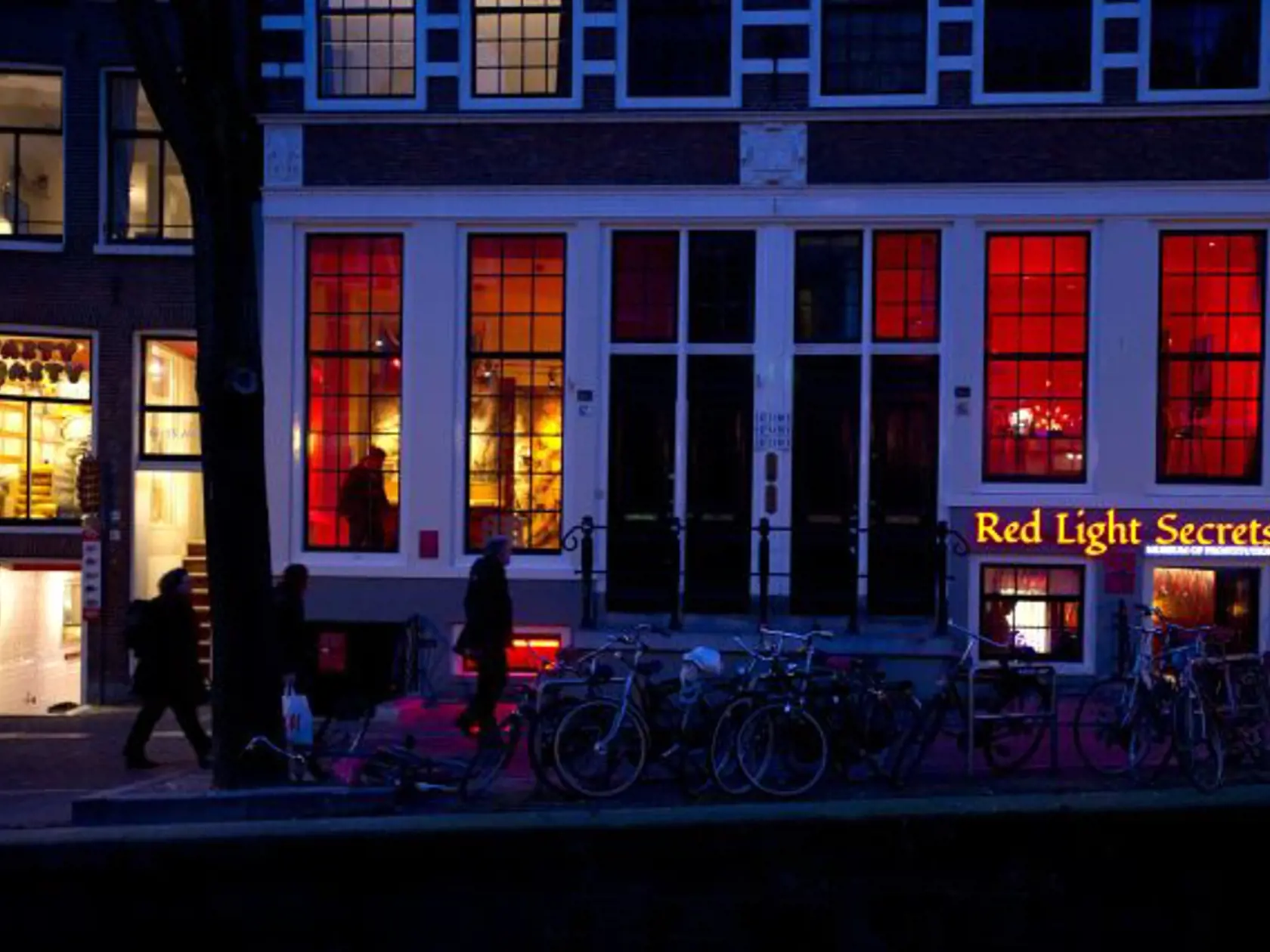 In this photo taken Tuesday, Feb. 4, 2014, the entrance of the 'Red Light Secrets' prostitution museum is seen, right, in Amsterdam. On any given evening, thousands of tourists stroll down the narrow streets of Amsterdam's famed Red Light District, gawking at ladies in lingerie who work behind windows, making a living selling sex for money. Now a small educational museum is opening in heart of the district that aims to show reality from the other side of the glass. Organizer Melcher de Wind says