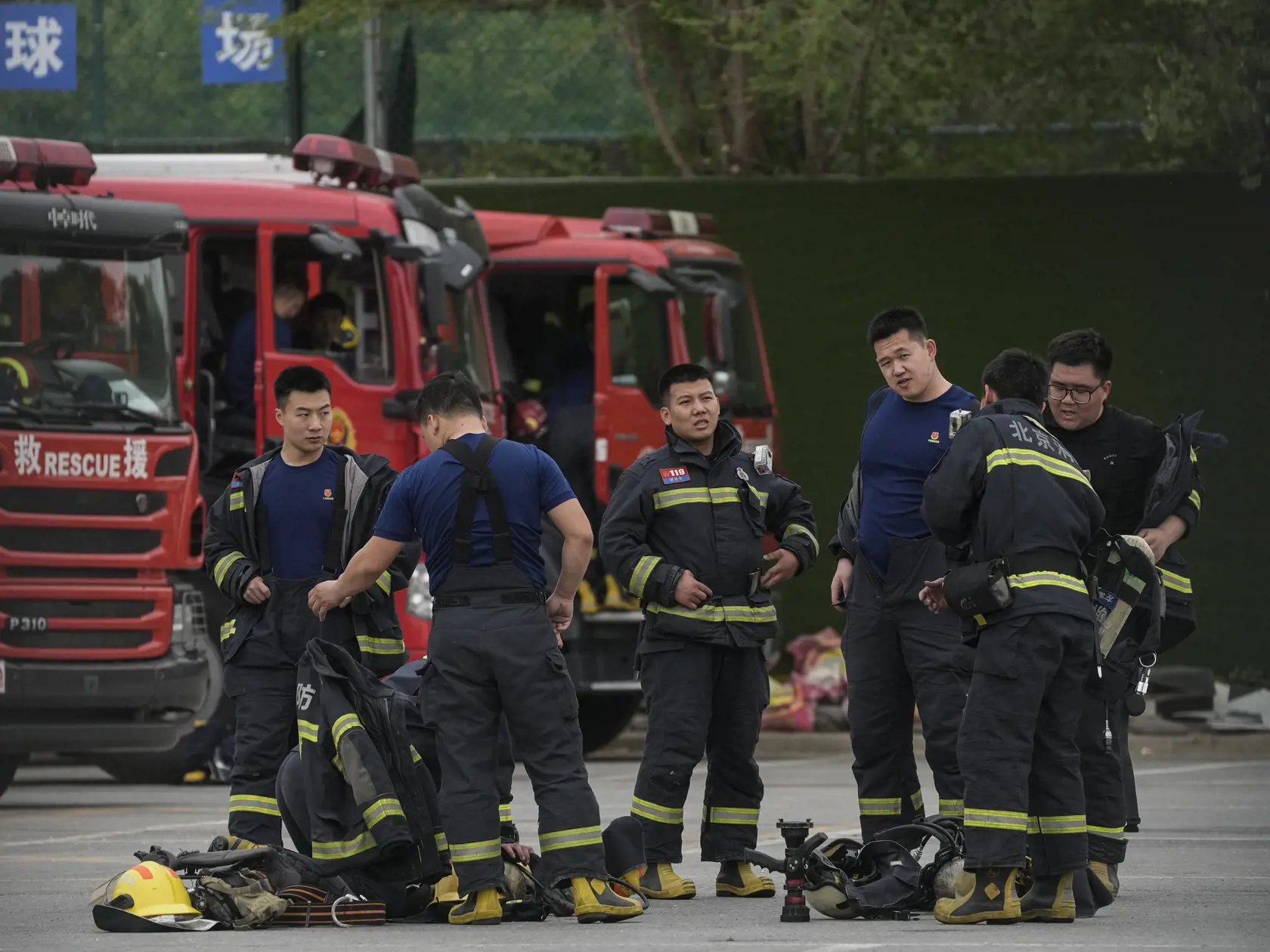 Hasiči sa vyzliekajú z kombinéz po cvičení vo verejnom parku v čínskom Pekinguv.