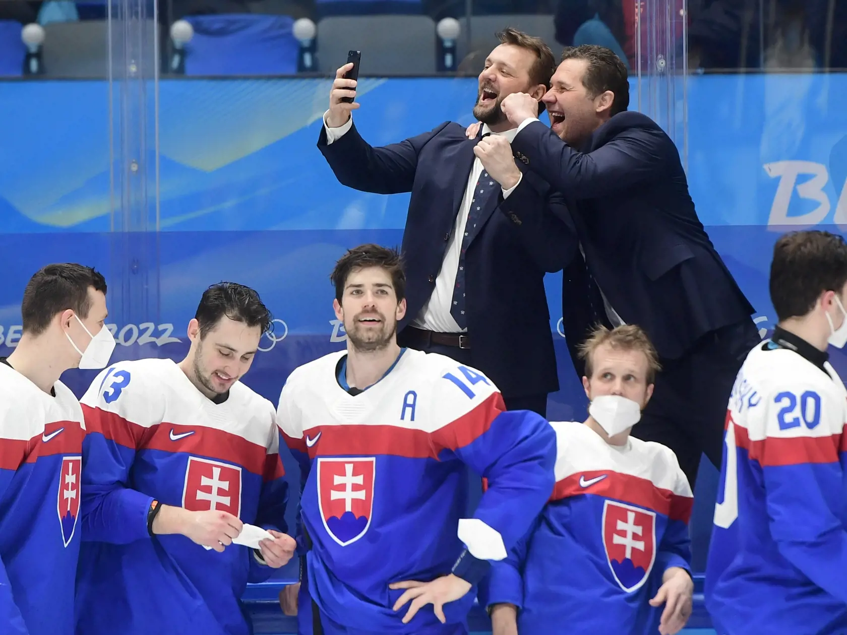 Na snímke hore asistent trénera vľavo Andrej Podkonický a tréner brankárov Ján Lašák a dole slovenskí hráči oslavujú po zisku bronzu po zápase olympijského turnaja v hokeji mužov o bronz Slovensko - Švédsko na ZOH 2022 v Pekingu v sobotu 19. februára 2022. FOTO TASR - Martin Baumann