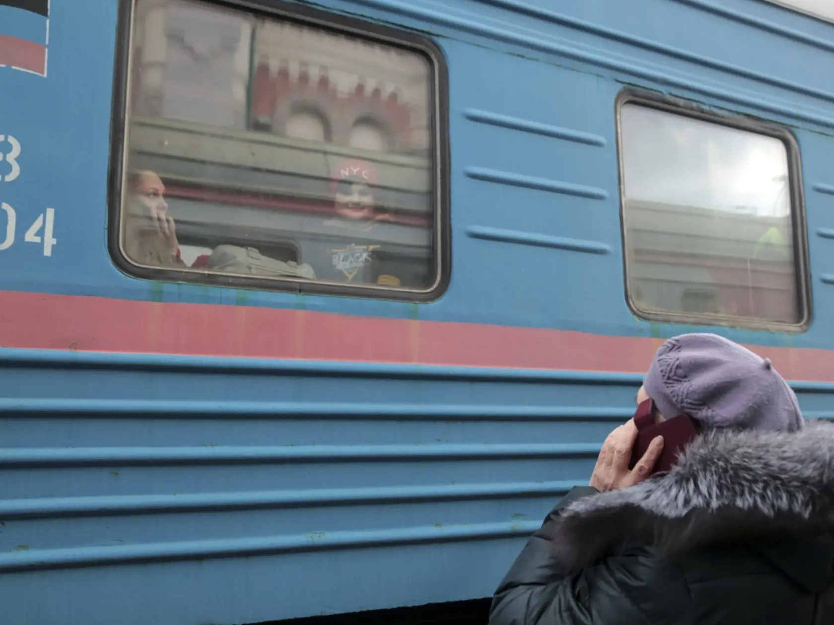 Žena hovorí cez telefón s príbuznými, ktorí sedia vo vlaku na železničnej stanici počas ich evakuácie do Ruska v meste Debaltseve, v oblasti kontrolovanej pro-ruskými militantmi na východe Ukrajiny 19. februára 2022.