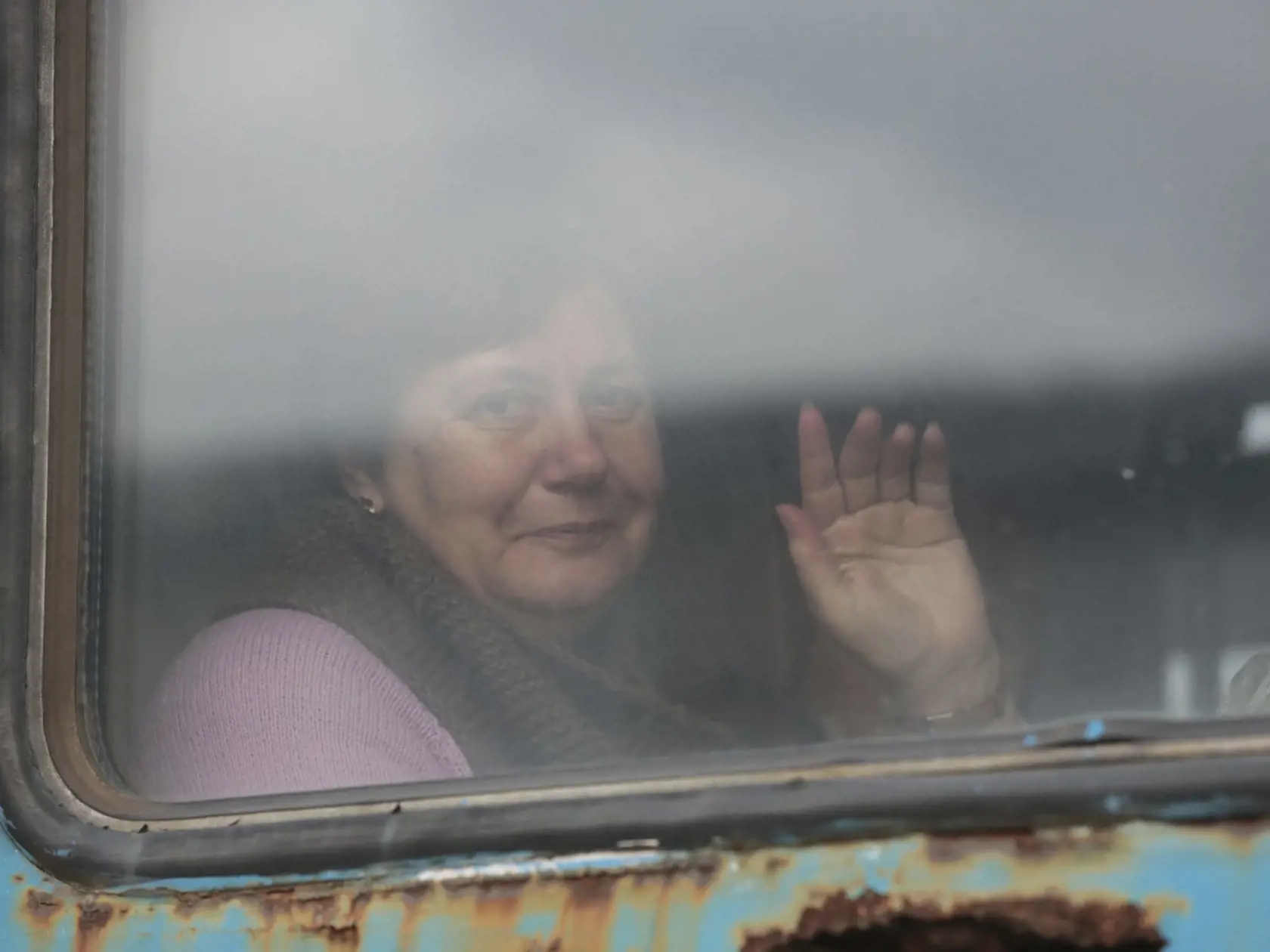 Staršia žena máva z vlaku na železničnej stanici počas jej evakuácie do Ruska v meste Debaltseve, v oblasti kontrolovanej pro-ruskými militantmi na východe Ukrajiny 19. februára 2022.