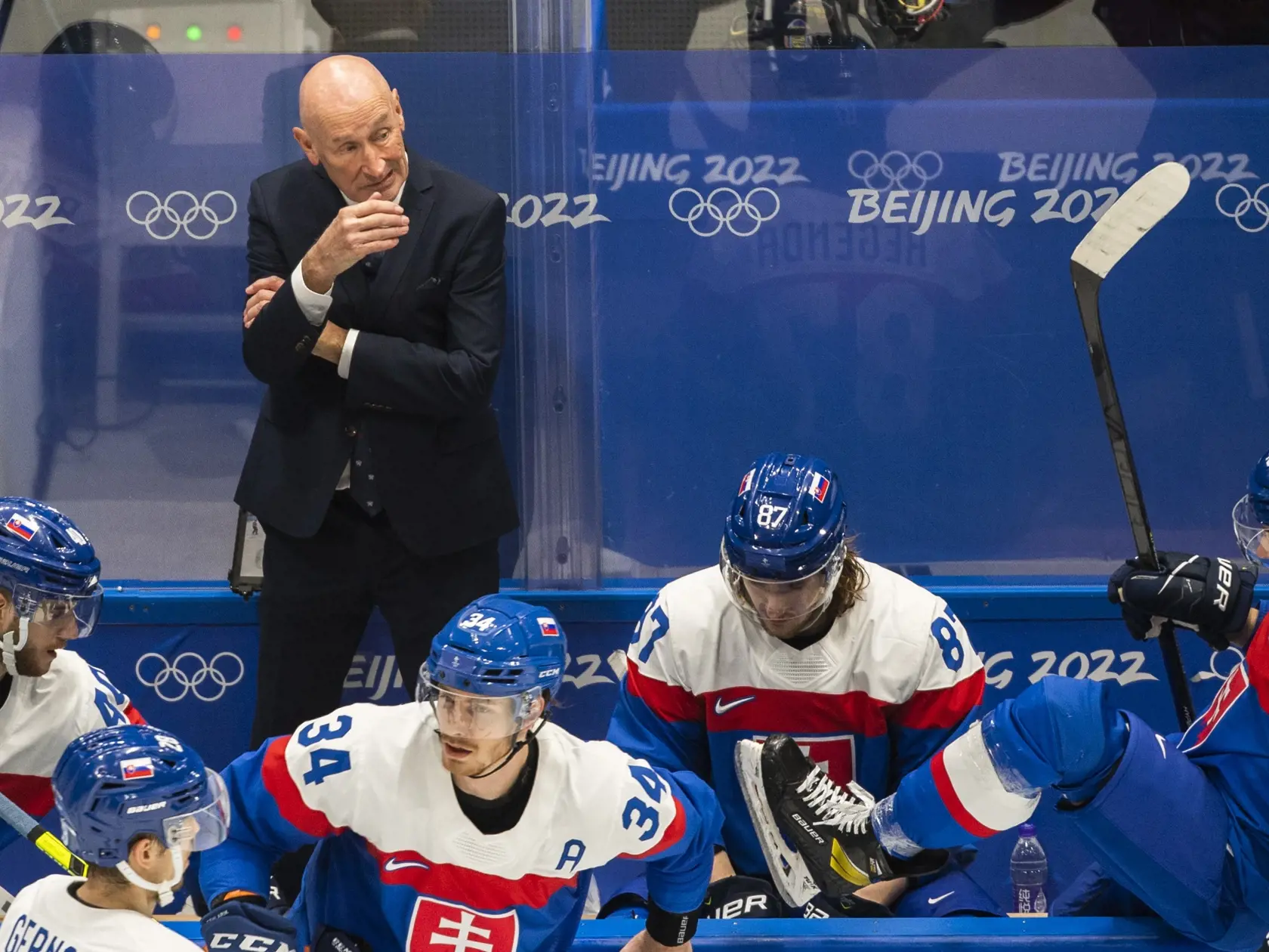 Na snímke hore tréner slovenskej hokejovej reprezentácie Craig Ramsay, dole zľava hráči Miloš Roman, Martin Gernát, Peter Cehlárik, Pavol Regenda a Samuel Takáč v zápase základnej C-skupiny hokejového turnaja mužov Lotyšsko - Slovensko na ZOH 2022 v Pekingu v nedeľu 13. februára 2022. FOTO TASR - Jaroslav Novák