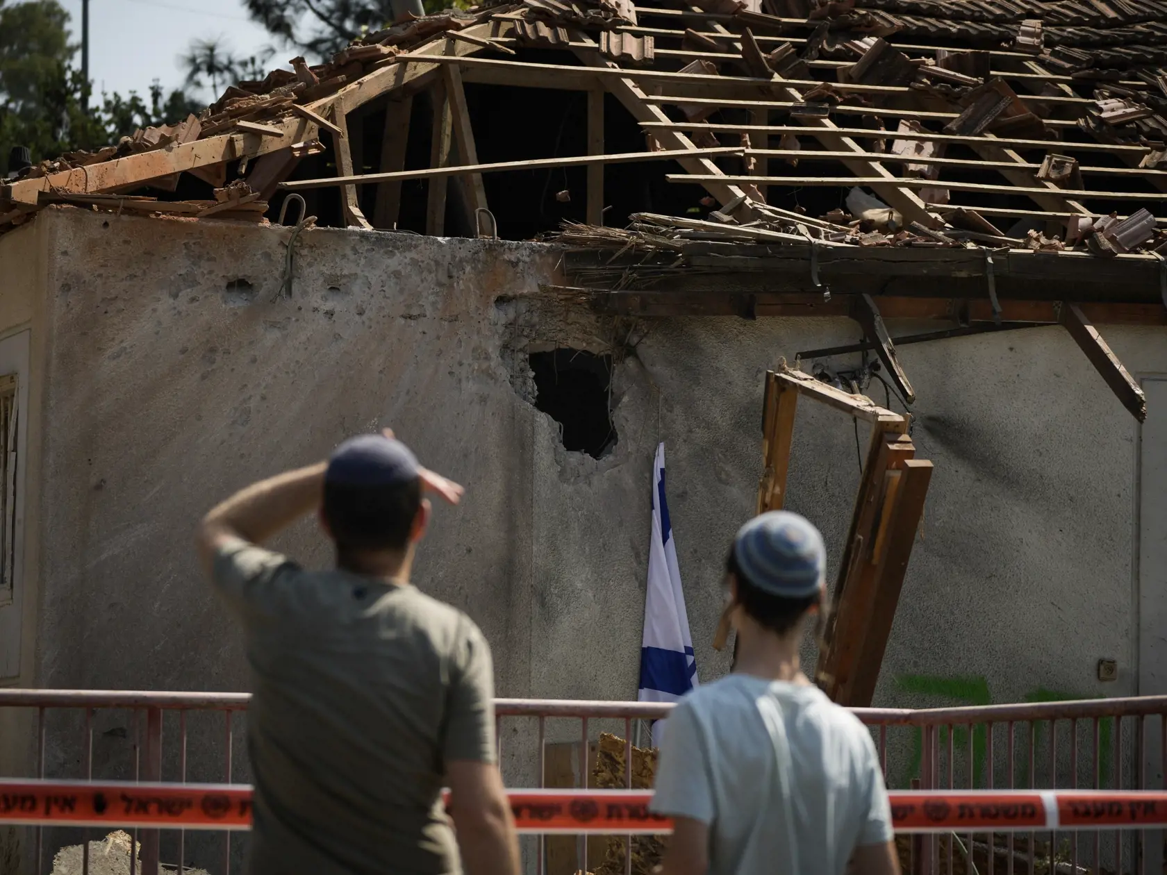 Ľudia sa pozerajú na dom, ktorý zasiahla raketa vypálená z Libanonu neďaleko mesta Safed na severe Izraela v stredu 25. septembra 2024.