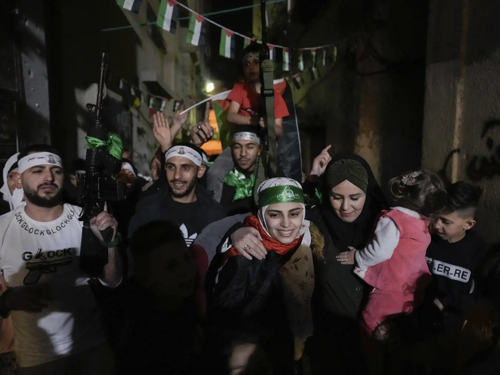 Na snímke bývalá palestínska väzenkyňa, ktorá má hlave čelenku Hamasu, sa víta s priateľmi a rodinnými príslušníkmi po jej prepustení v palestínskom utečeneckom tábore v Nábuse na Západnom brehu Jordánu 24. novembra 2023.  Hamas v piatok počas prvého dňa prímeria prepustil prvých 24 z približne 240 rukojemníkov, ktorých zadržiava v Pásme Gazy od útoku na Izrael.