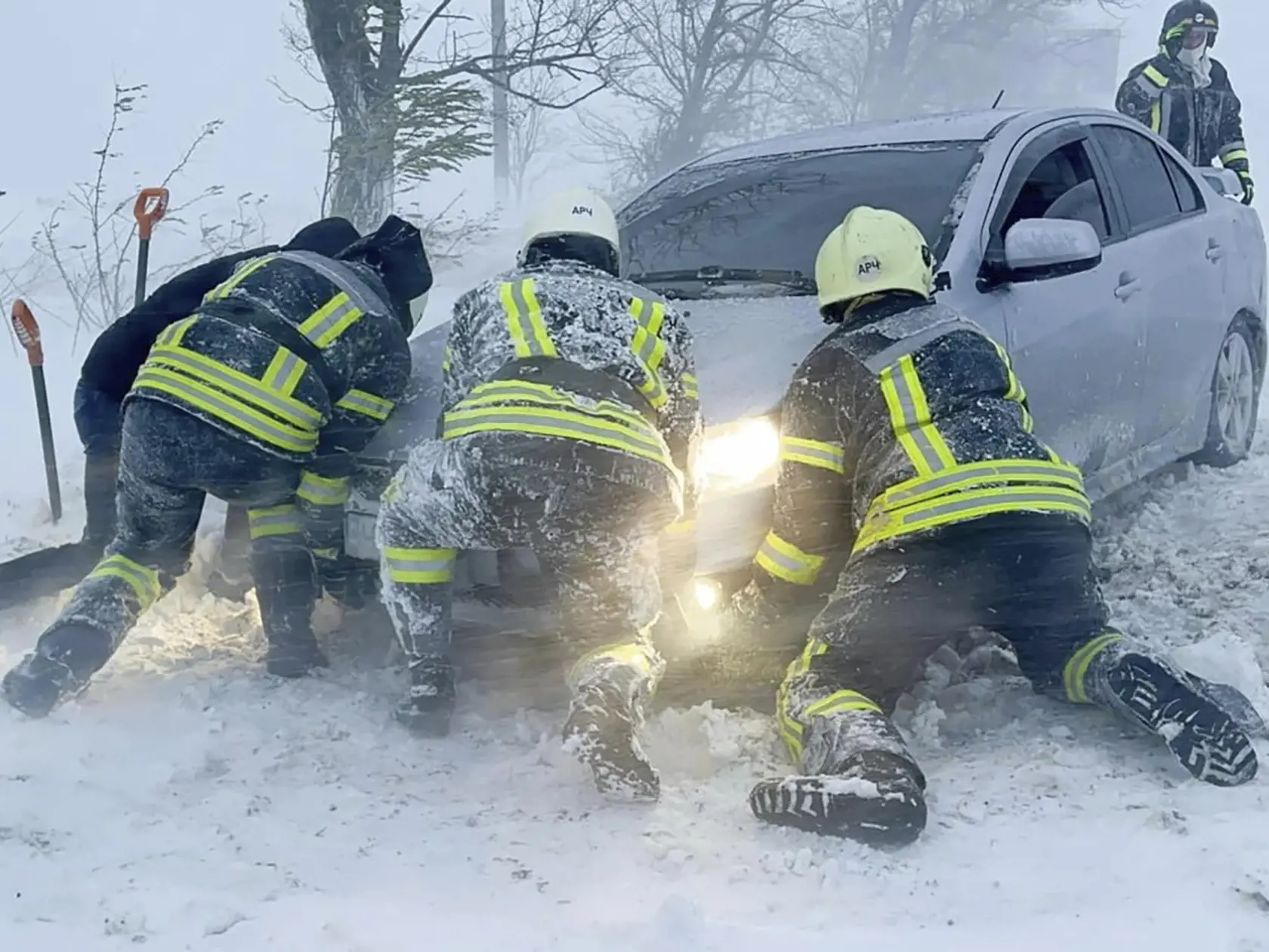 Ukrajinskí záchranári snažia odtlačiť auto, ktoré uviazlo na ceste počas snehovej víchrice v Odeskej oblasti na juhu Ukrajiny v pondelok 27. novembra 2023.