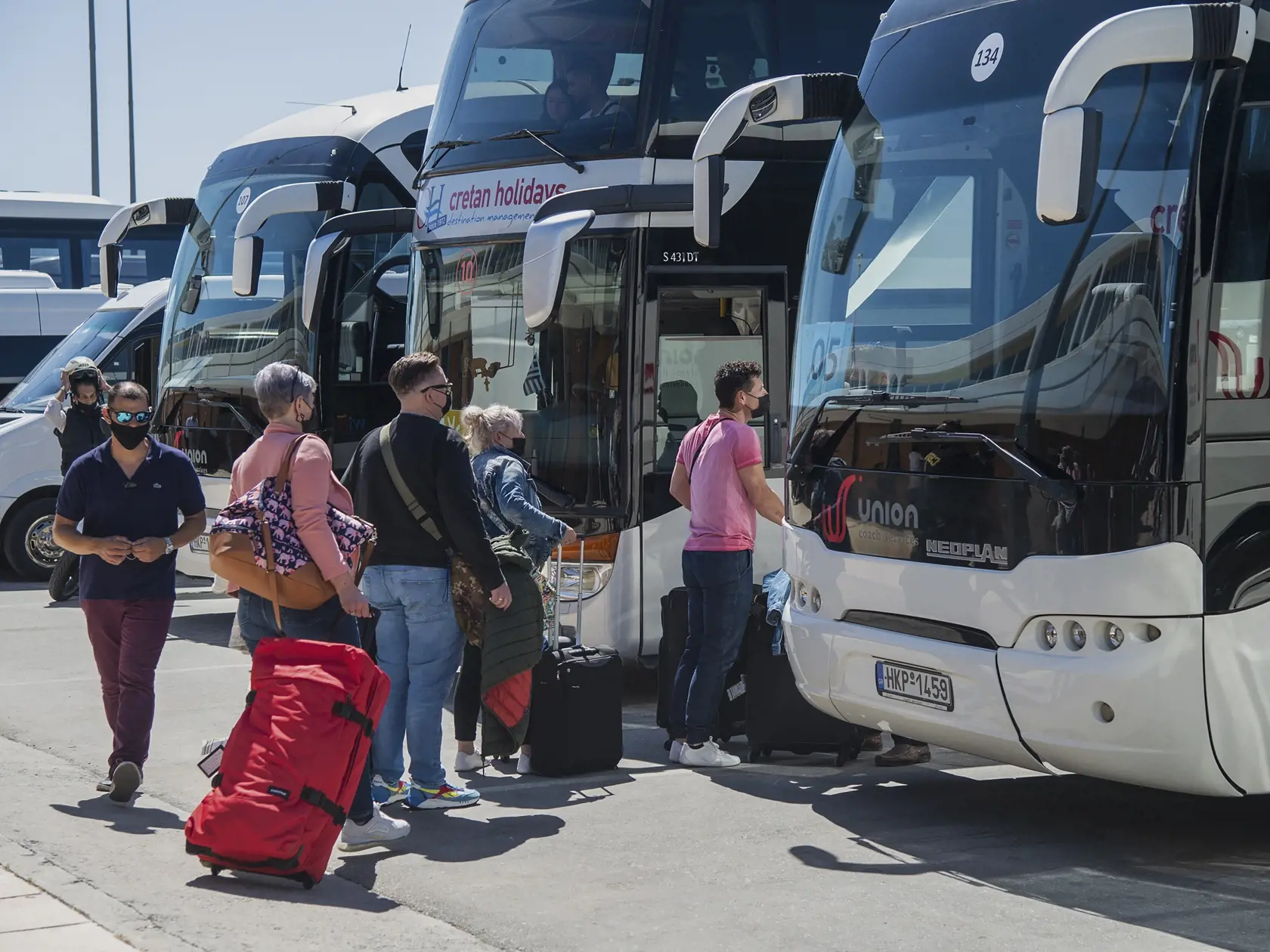 Cestujúci z Hannoveru nastupujú do autobusov po prílete na medzinárodné letisko v Heraklione na gréckom ostrove Kréta 14. mája 2021. V Grécku sa v piatok oficiálne začala letná dovolenková sezóna. Vláda i cestovné kancelárie dúfajú, že po nevydarenej vlaňajšej letnej sezóne, poznačenej koronavírusovou pandémiou, prinesie tohtoročné leto navýšenie tržieb, čo je pre Grécko - krajinu závislú od cestovného ruchu - veľmi potrebné.