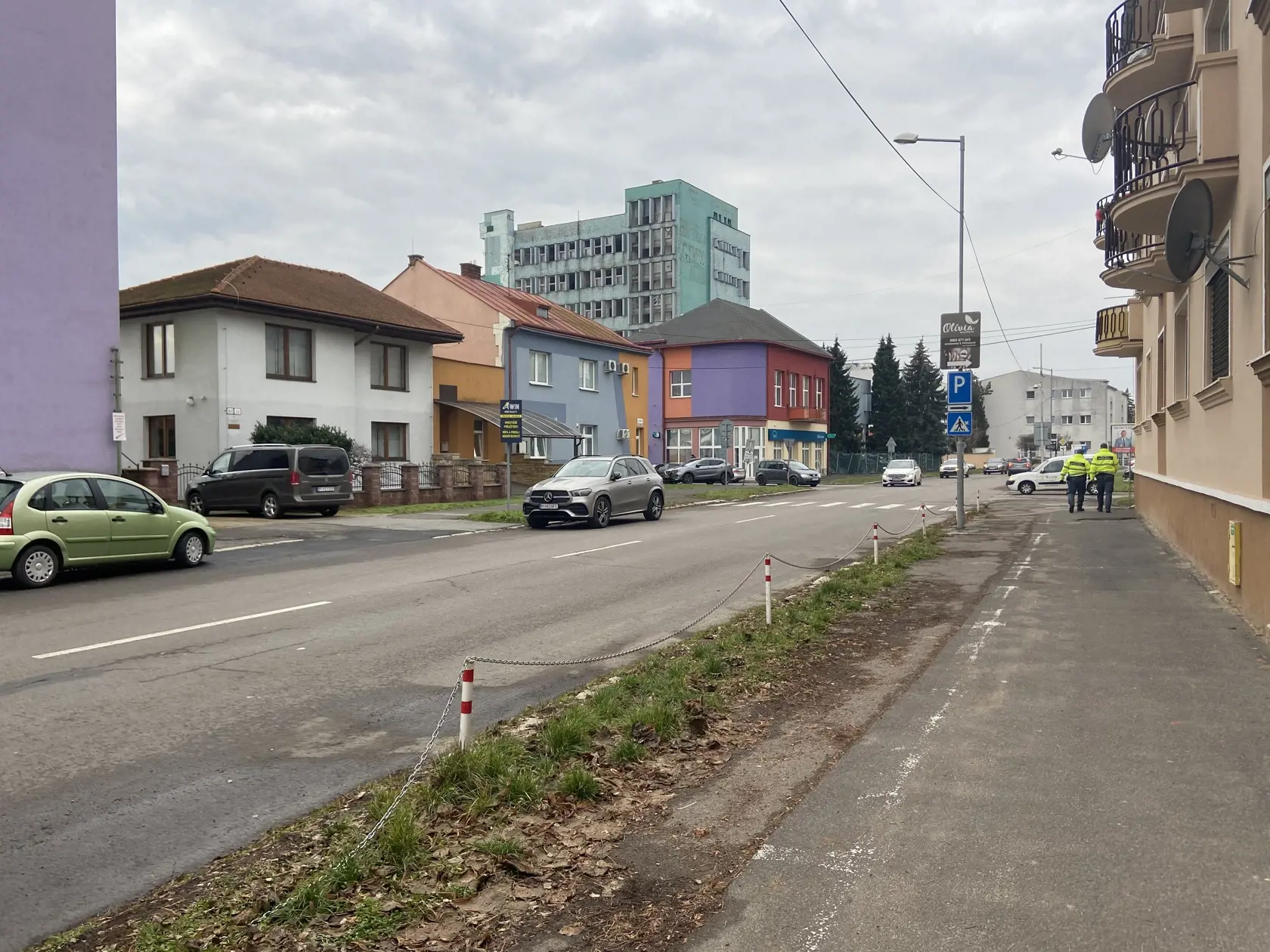 Žena mala vyberať peniaze z bavnkomatu, ktorý je budove vzadu vpravo. (fialovo bordovo tehlovej farby)