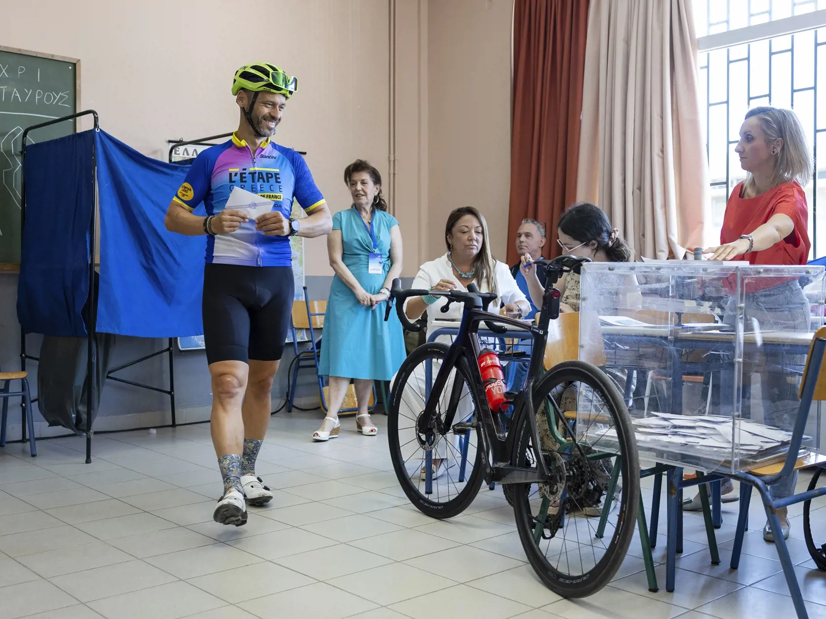 KK15 Atény - Cyklista sa pripravuje hlasovať vo volebnej miestnosti vo voľbách do Európskeho parlamentu v Aténach v nedeľu 9. júna 2024. Eurovoľby sa konali od 6. do 9. júna.  FOTO TASR/AP

A biker prepares to cast a ballot inside a school room which is used as a voting station during the European Elections in Athens, Sunday, June 9, 2024. Polling stations opened across Europe on Sunday as voters from 20 countries cast ballots in elections that are expected to shift the European Union's parliame