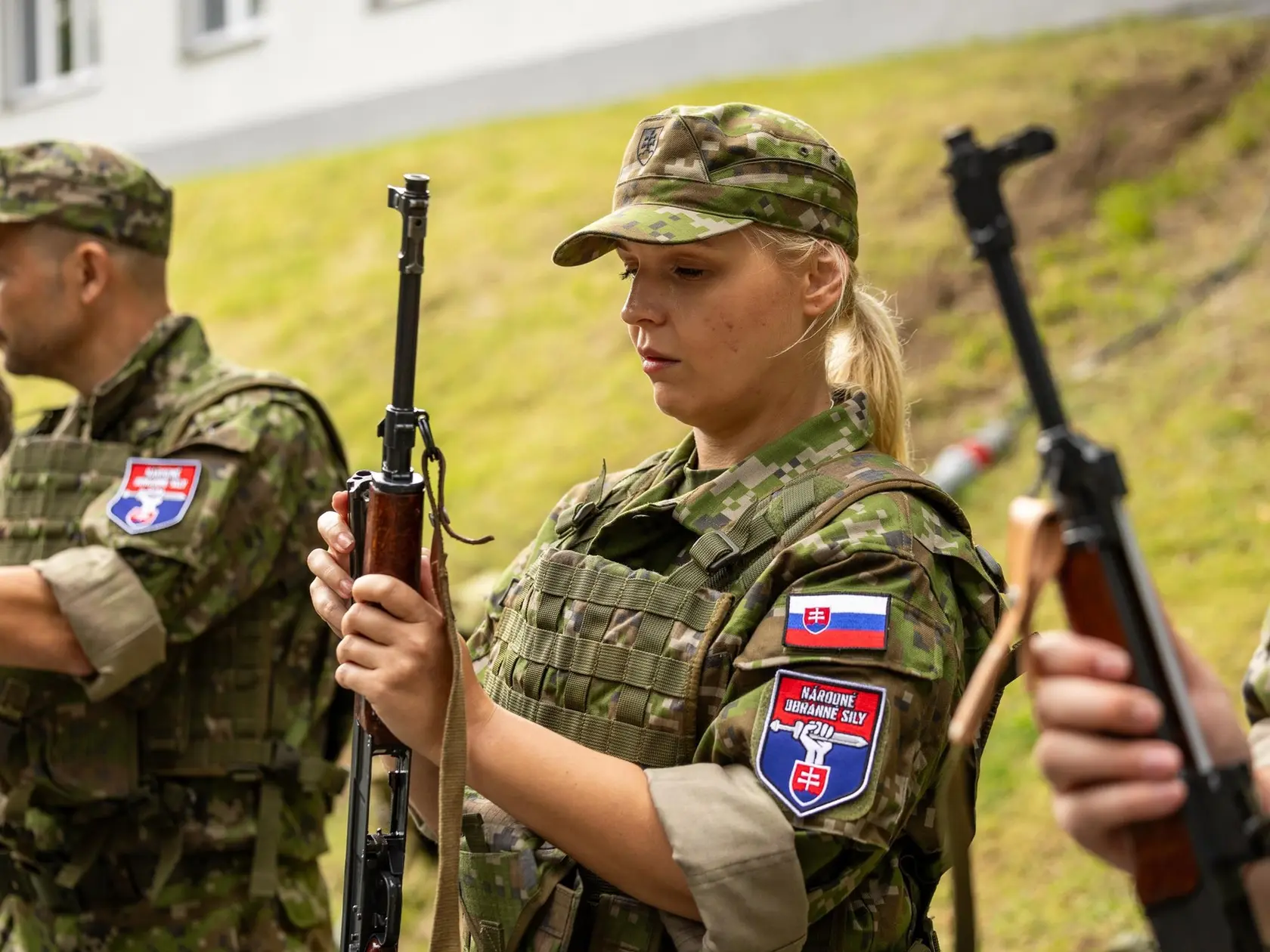 Zuzana Plevíková, blond koaličná poslankyňa zo Smeru počas výcviku Národných obranných síl: v maskáčoch a so zbraňou.