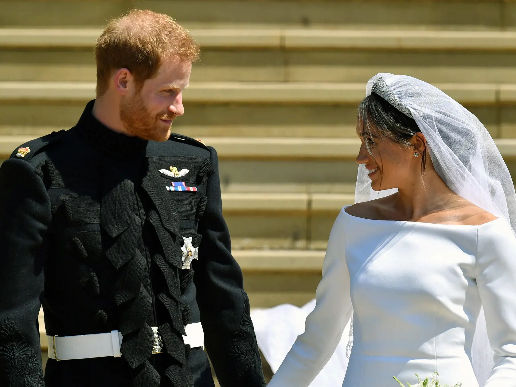 Na archívnej snímke z 19. mája 2018 britský princ Harry a Meghan Markleová odchádzajú po sobáši v Kaplnke sv. Juraja na kráľovskom zámku vo Windsore.