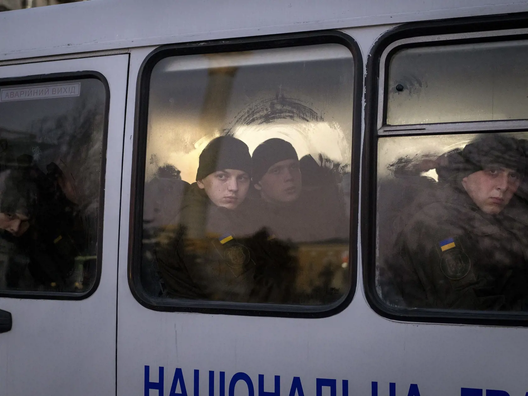 Príslušníci Národnej gardy Ukrajiny sa pozerajú z okna autobusu pri jazde v centre Kyjeva 14. februára 2022. Rusko zhromaždilo pri hraniciach Ukrajiny viac ako 100.000 vojakov a žiada ústupky od NATO vrátane ubezpečenia, že vojenská aliancia neprijme žiadnych nových východných členov. Časť ruských vojenských cvičení, ktoré sa v súčasnosti konajú v rôznych častiach krajiny na súši i na mori, ako i v Bielorusku, sa chýli ku koncu.