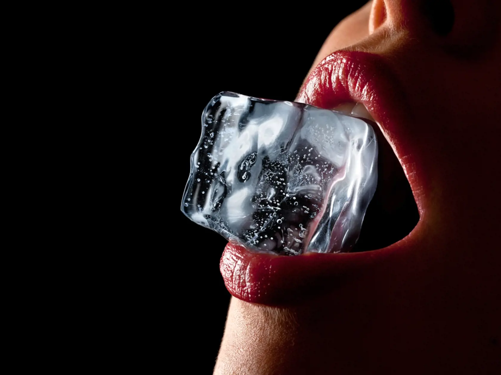 Ice,Cube,In,A,Woman's,Mouth,Against,Black,Background.