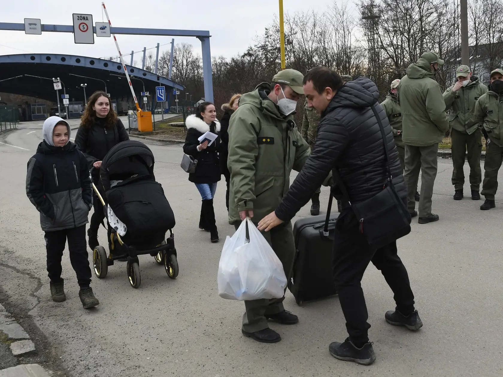 Utečenci z Ukrajiny prechádzajú cez hraničný priechod vo Vyšnom Nemeckom, uprostred im pomáha colník. Vyšné Nemecké, 25. februára 2022. FOTO TASR - Milan Kapusta