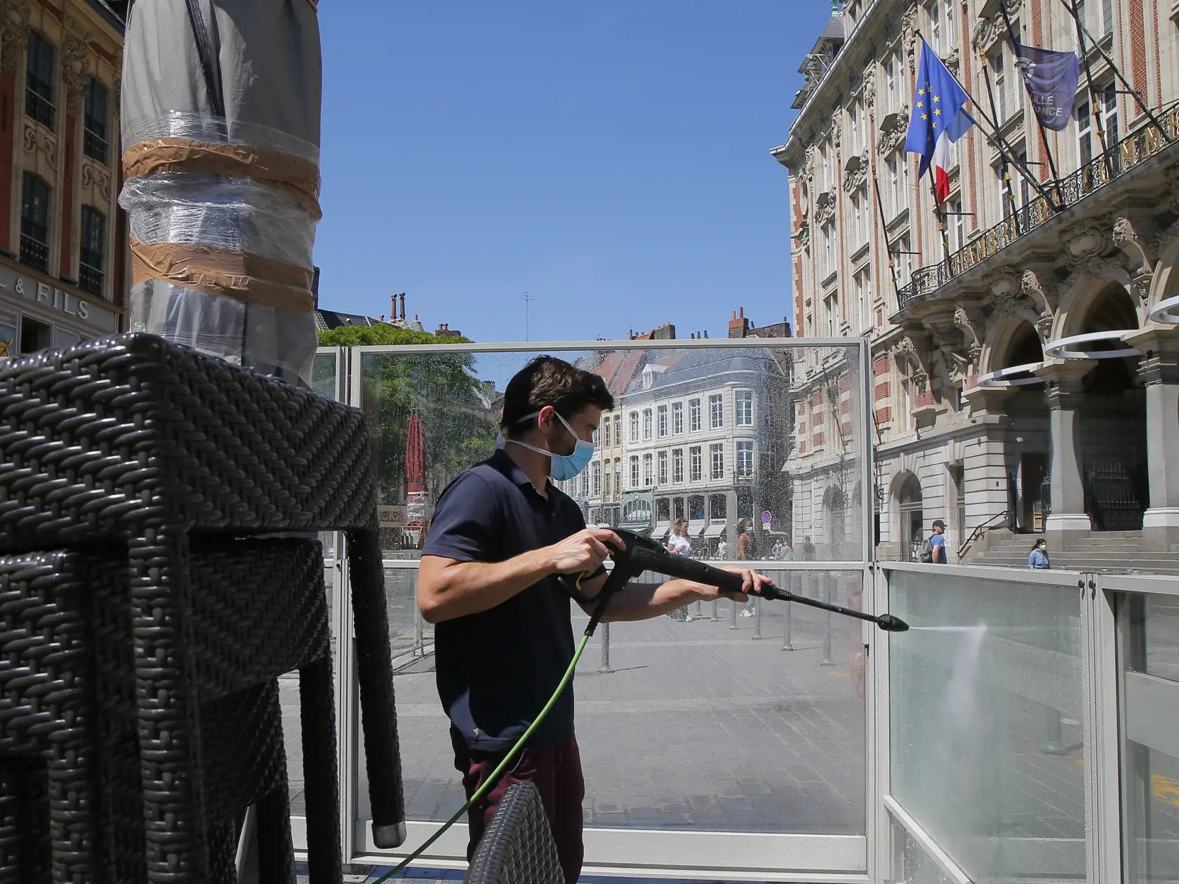 Zamestnanec kaviarne čistí vonkajšiu terasu pred jej znovuotvorením v Lille.
