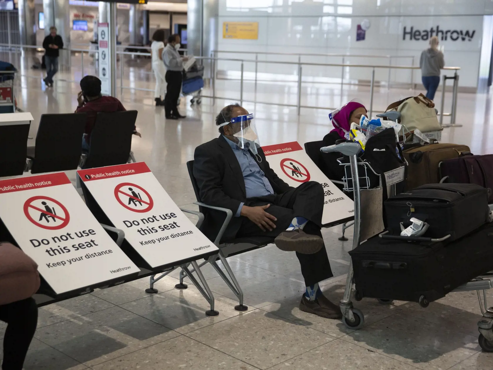 Pasažier s ochranným štítom na zabránenie šírenia nového koronavírusu sedí po prílete na letisko Heathrow v Londýne.