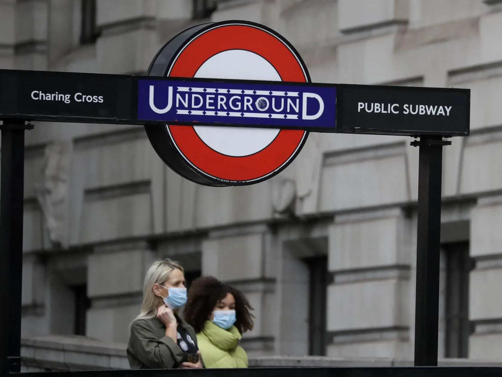Ženy s ochrannými rúškami na zabránenie šírenia nového koronavírusu prechádzajú okolo stanice metra Charing Cross Station v Londýne.